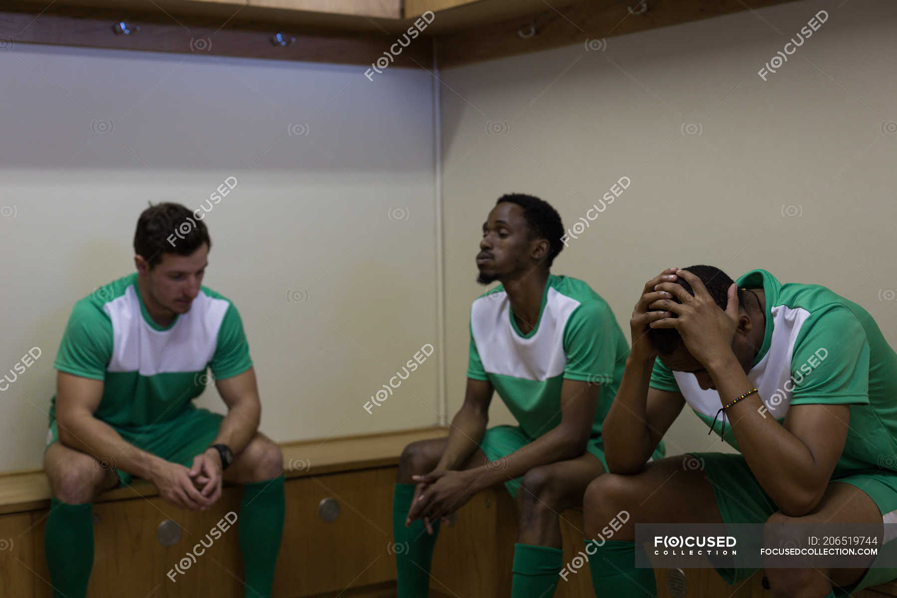 Tense football players sitting on dressing room — Worried, black Stock Photo 206519744