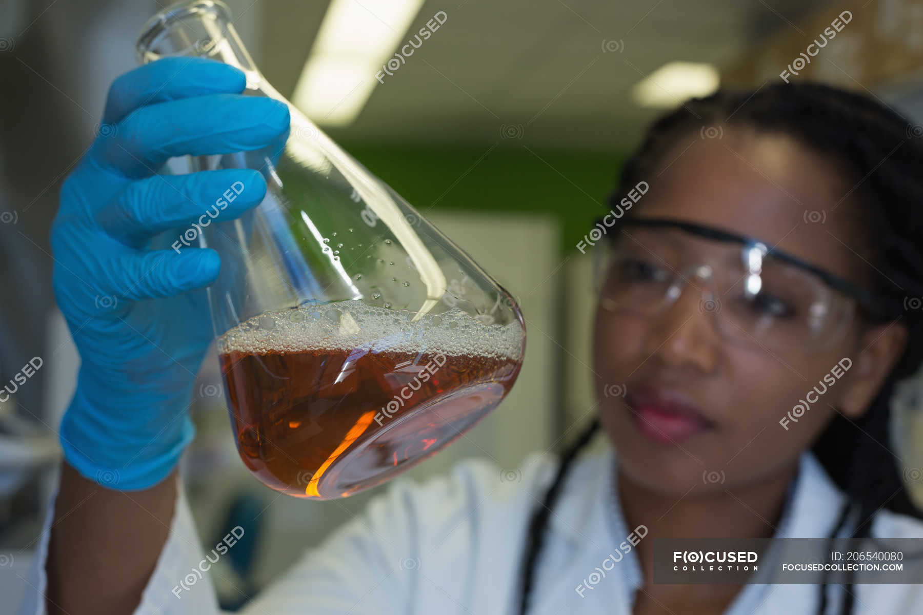 Scientist checking a solution in conical flask at lab — test