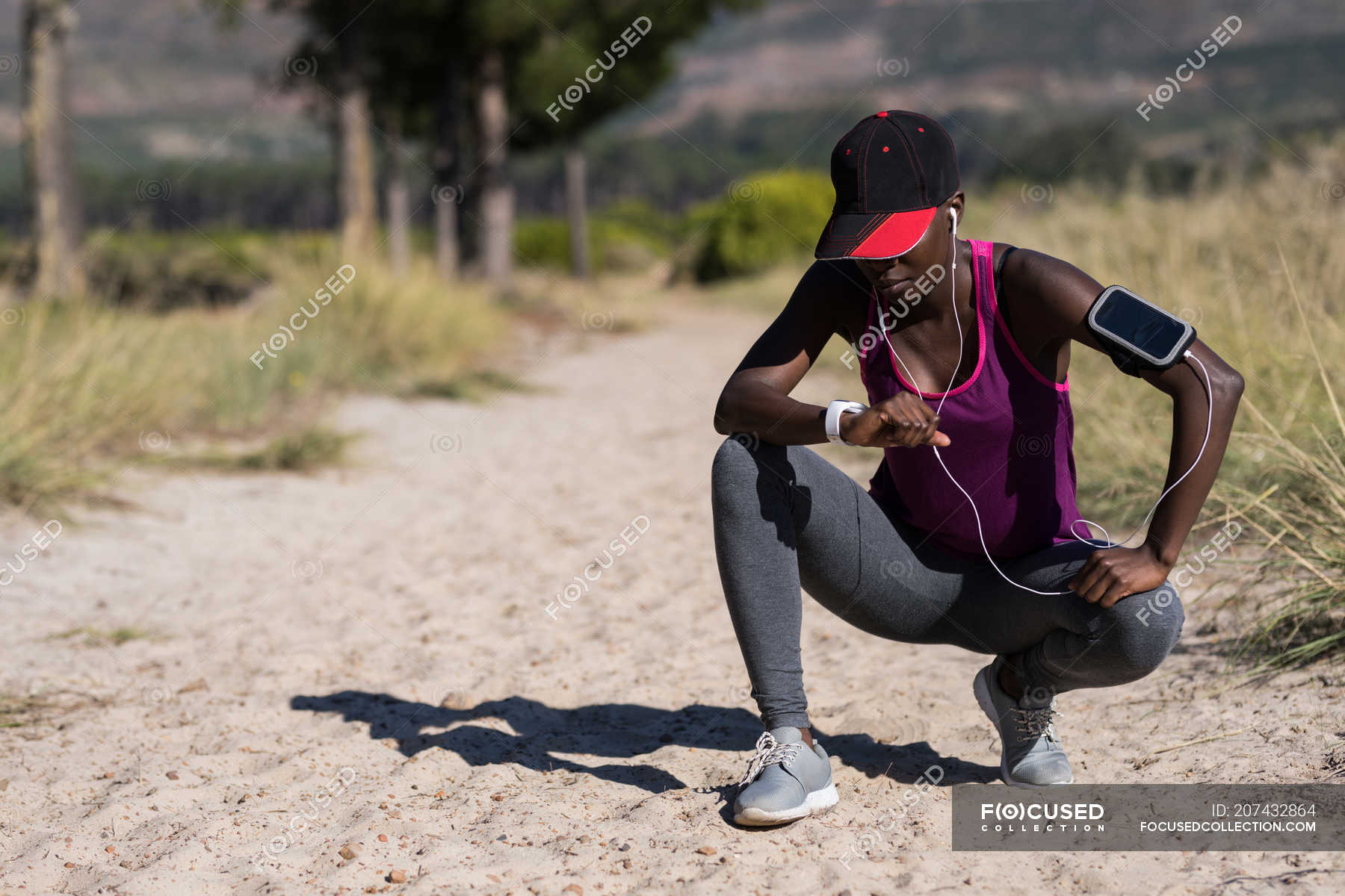 Exhausted female athlete crouching in the forest — sunny, environment Stock Photo 207432864