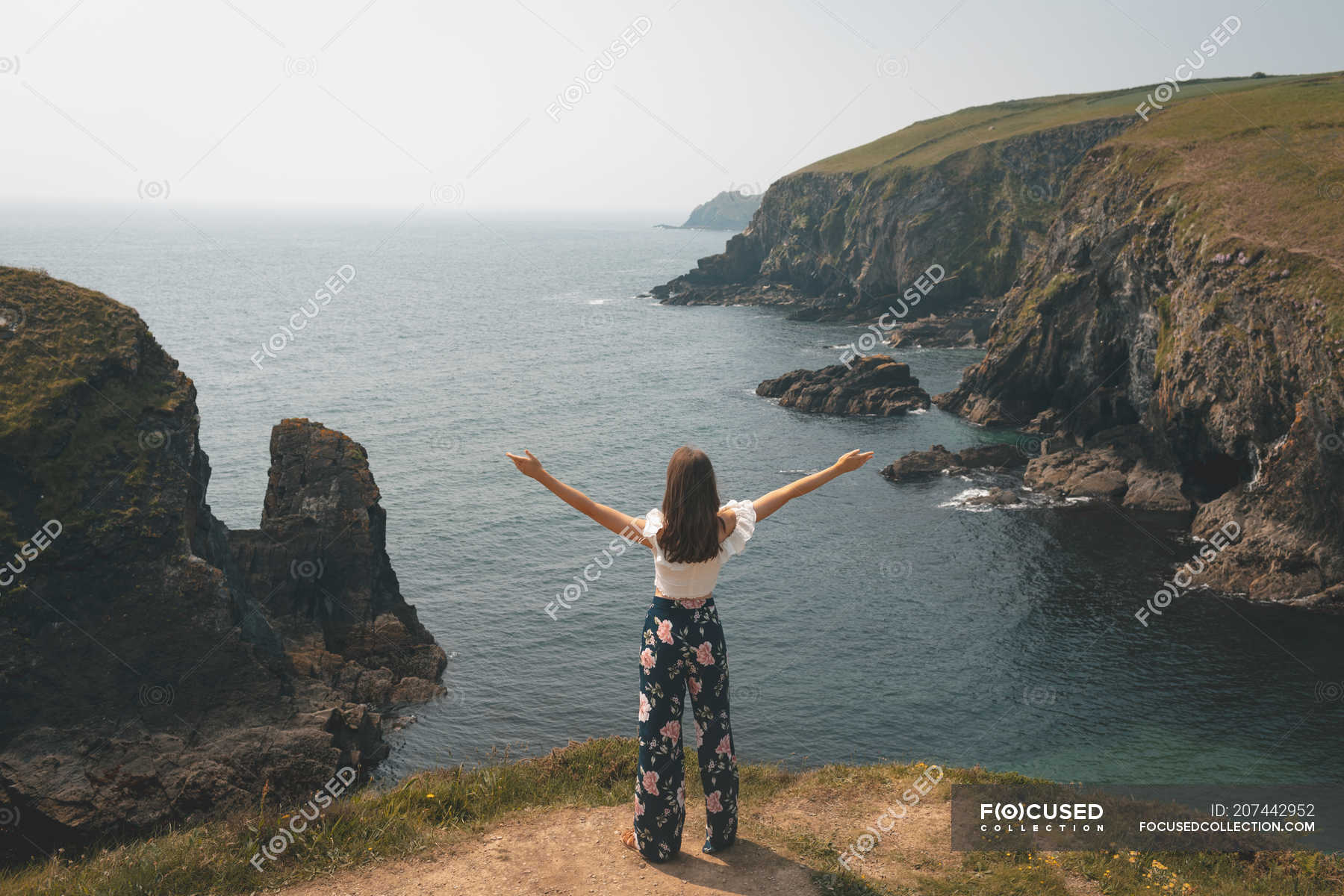 Rear View Of Woman Standing At The Edge Of The Cliff With Her Hands Spread — Isolated Lifestyle