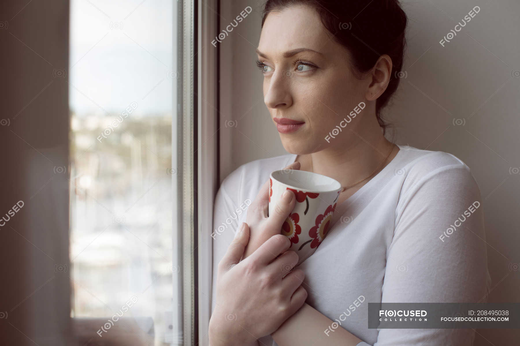 Thoughtful Woman Holding Coffee Mug And Looking Through Window