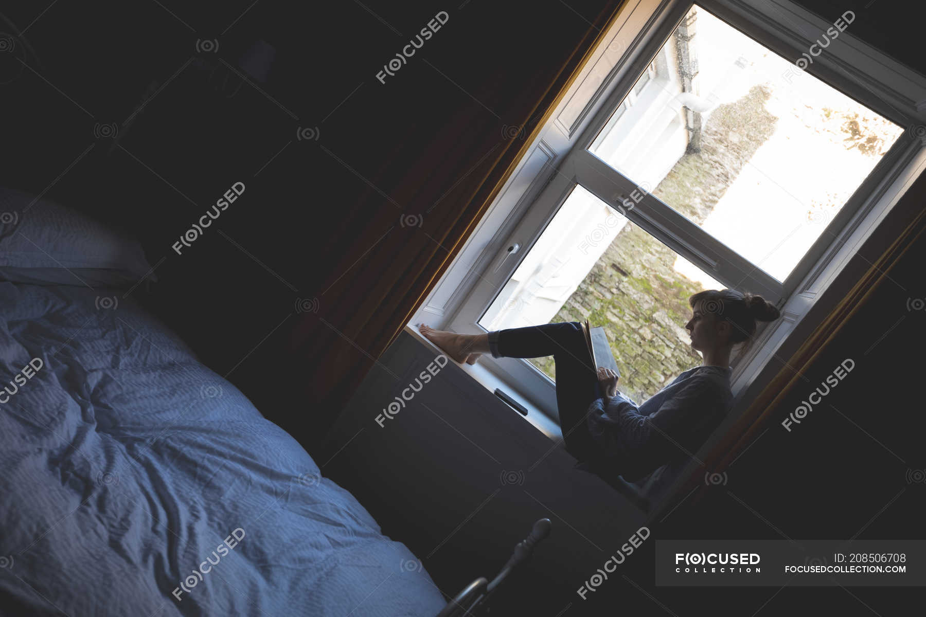 Woman reading book on window sill in bedroom at home — fashion, glass -  Stock Photo | #208506708