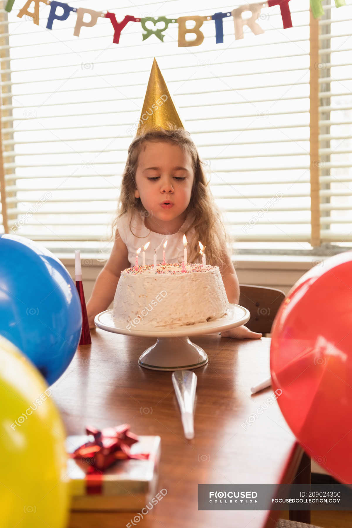 Kleines Mädchen bläst zu Hause die Kerzen auf ihrem Geburtstagskuchen