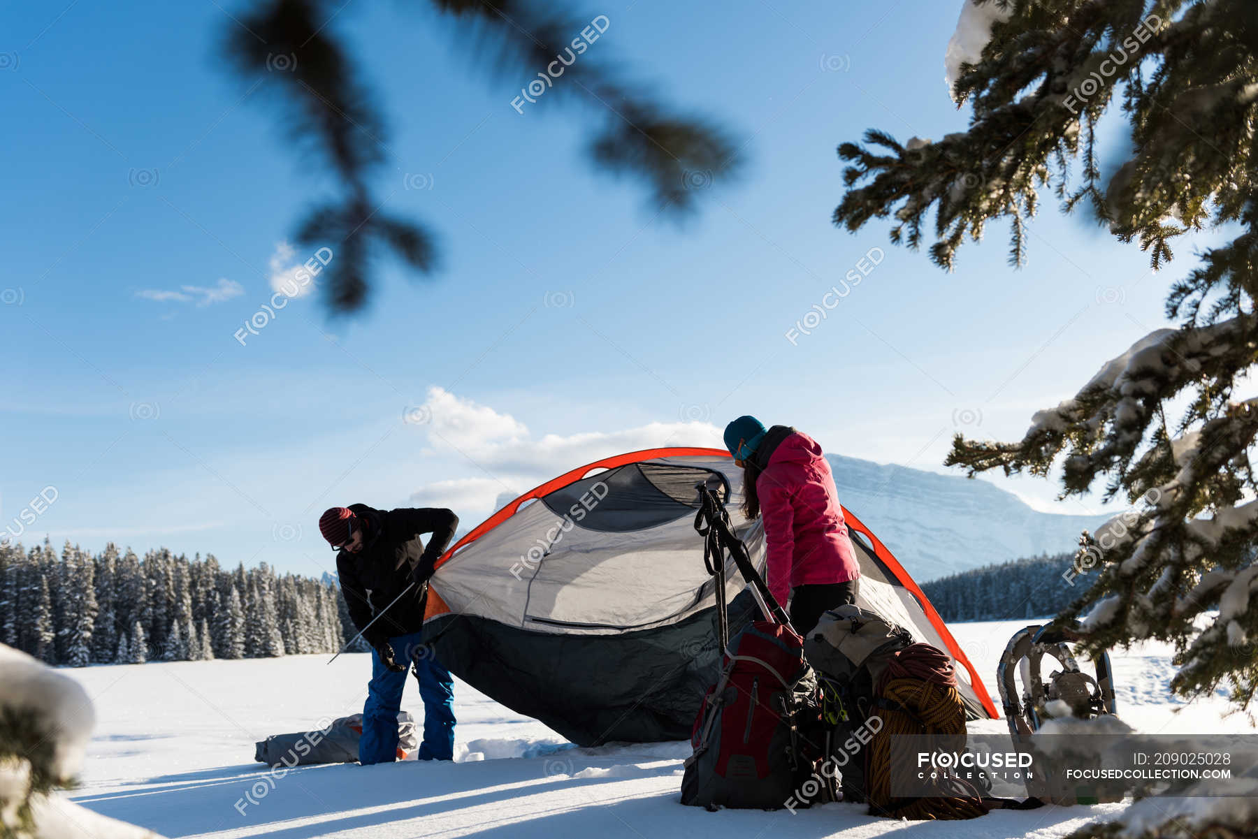 Couple pitching tent in snowy landscape during winter. — nature