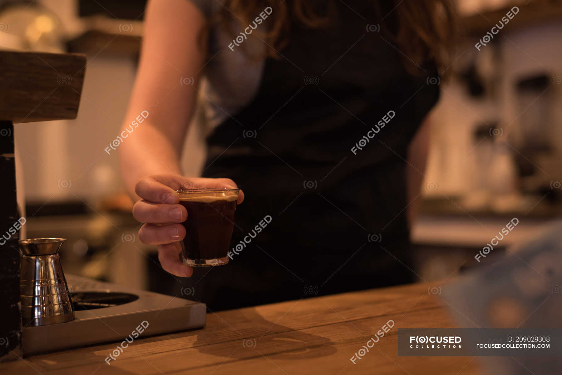 Mid section of female barista serving coffee at counter in cafe ...