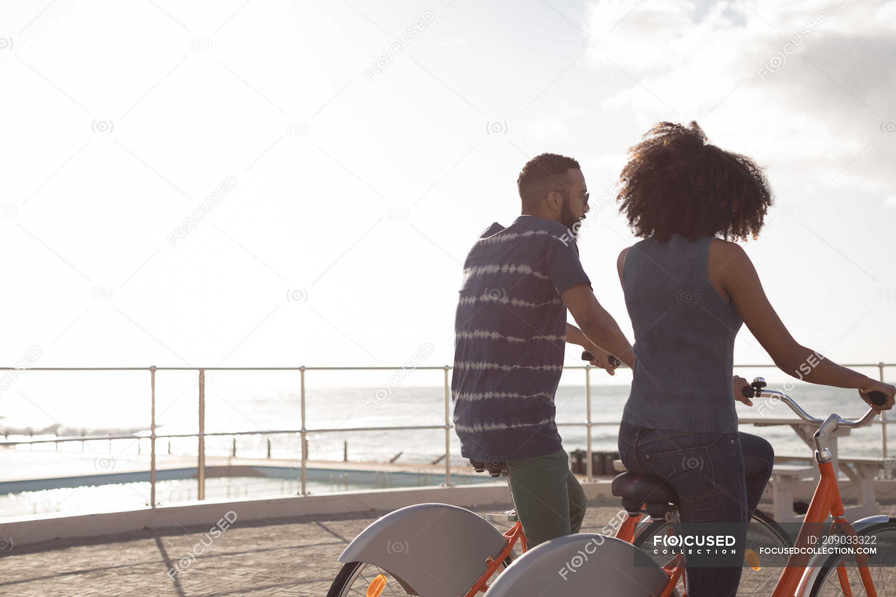 Romantic couple enjoying cycle ride near beach — dating, clouds - Stock ...