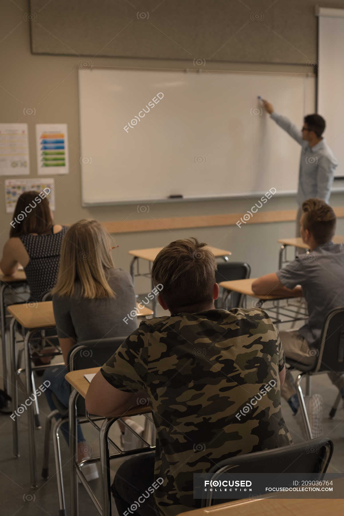 Teacher teaching students on whiteboard in classroom — Guidance