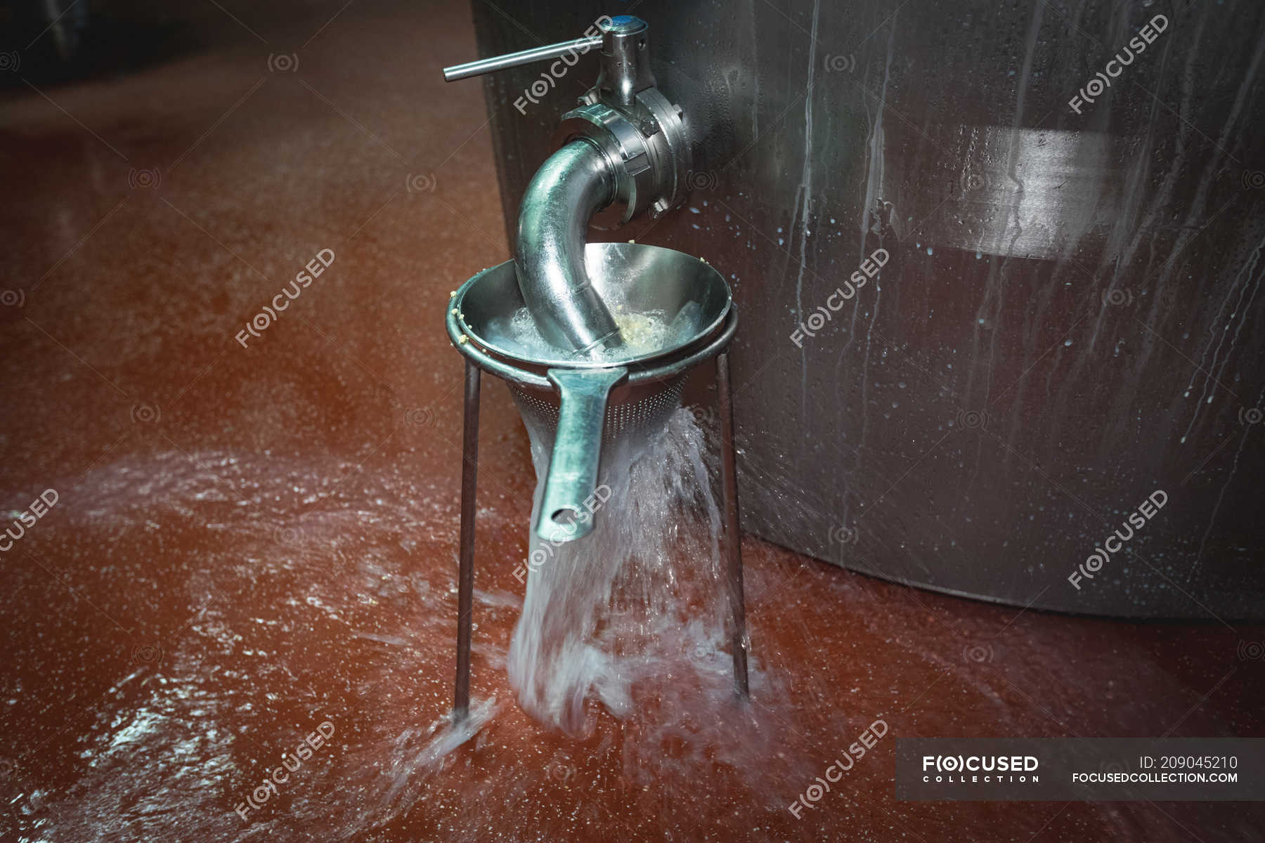 Liquid being filtered and overflowing from the tank in food factory