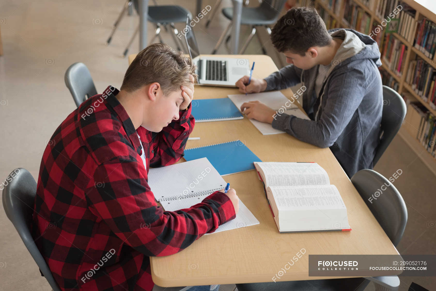 College students studying in library at university — sitting, pen