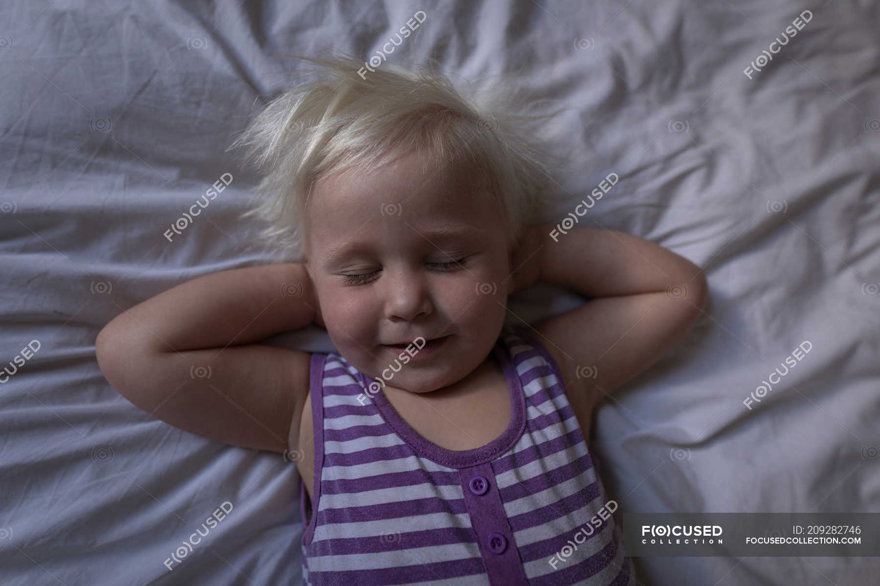Toddler girl sleeping with hands behind head on bed in bedroom. — apartment, people Stock