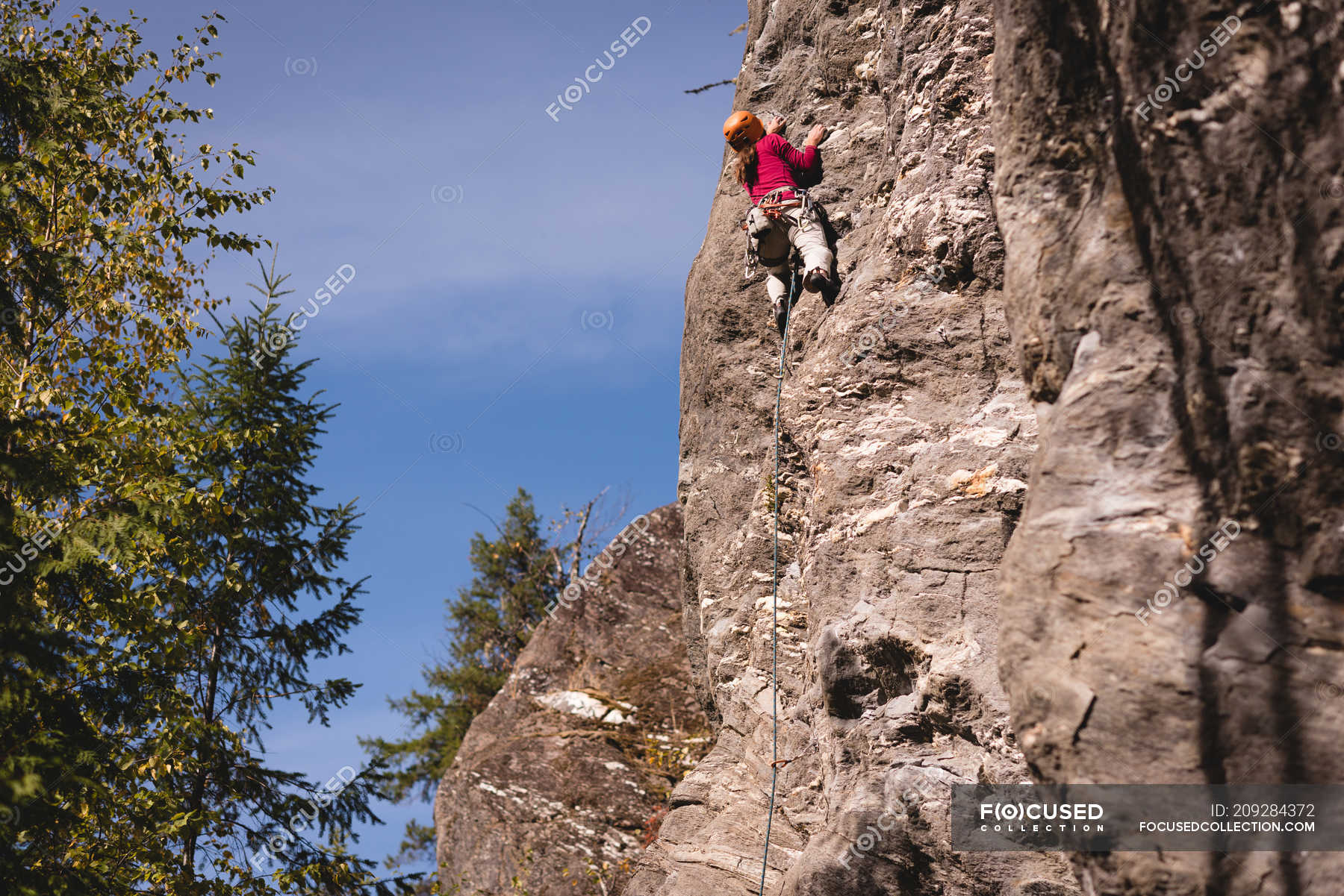 Mid section of female climber climbing the rocky mountain — adventure