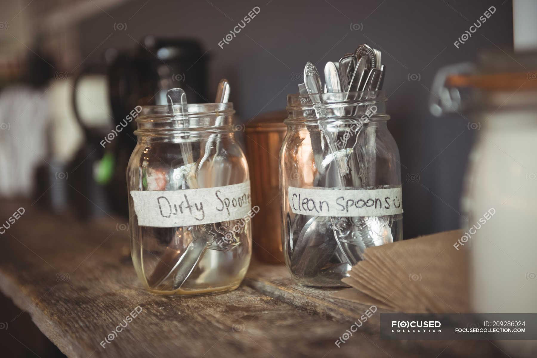 Clean and dirty spoons in jar on table — cafeteria, wooden Stock