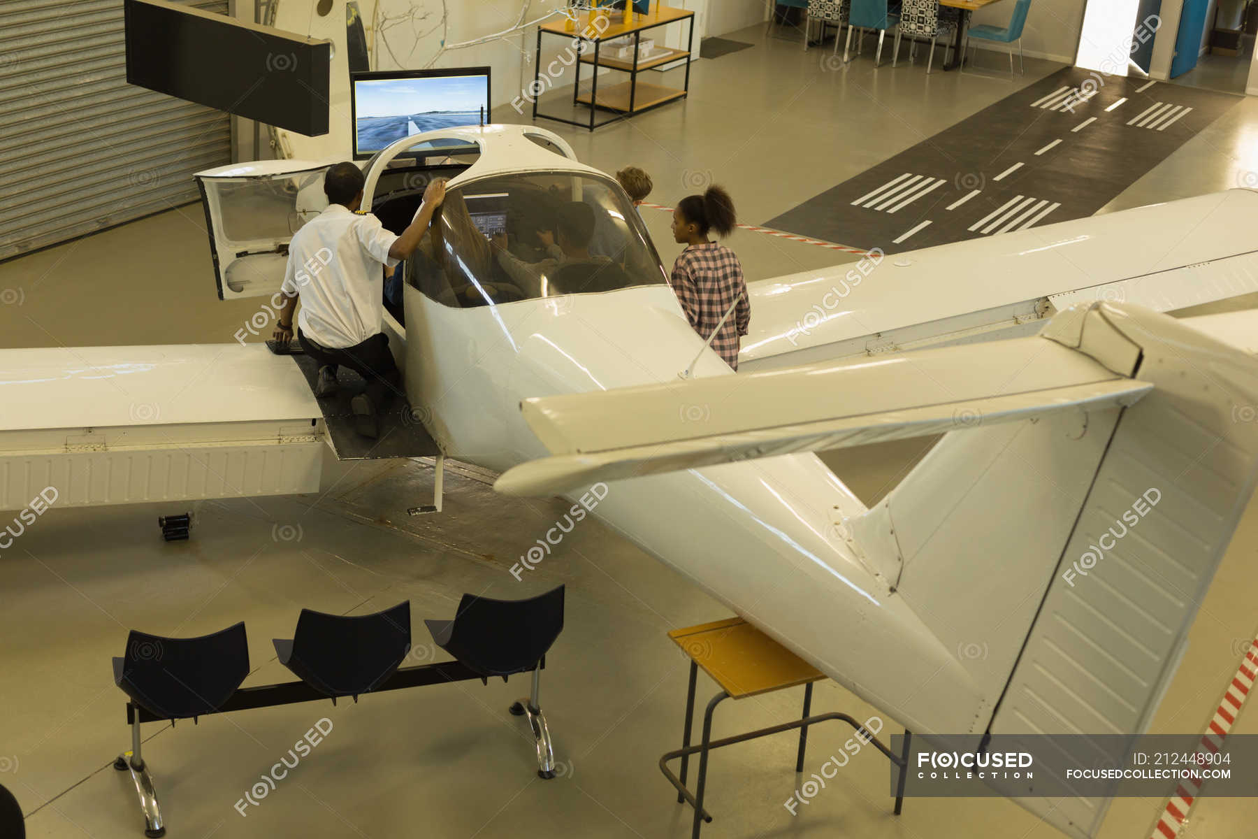 Male pilot explaining about aeroplane to kids in training institute ...