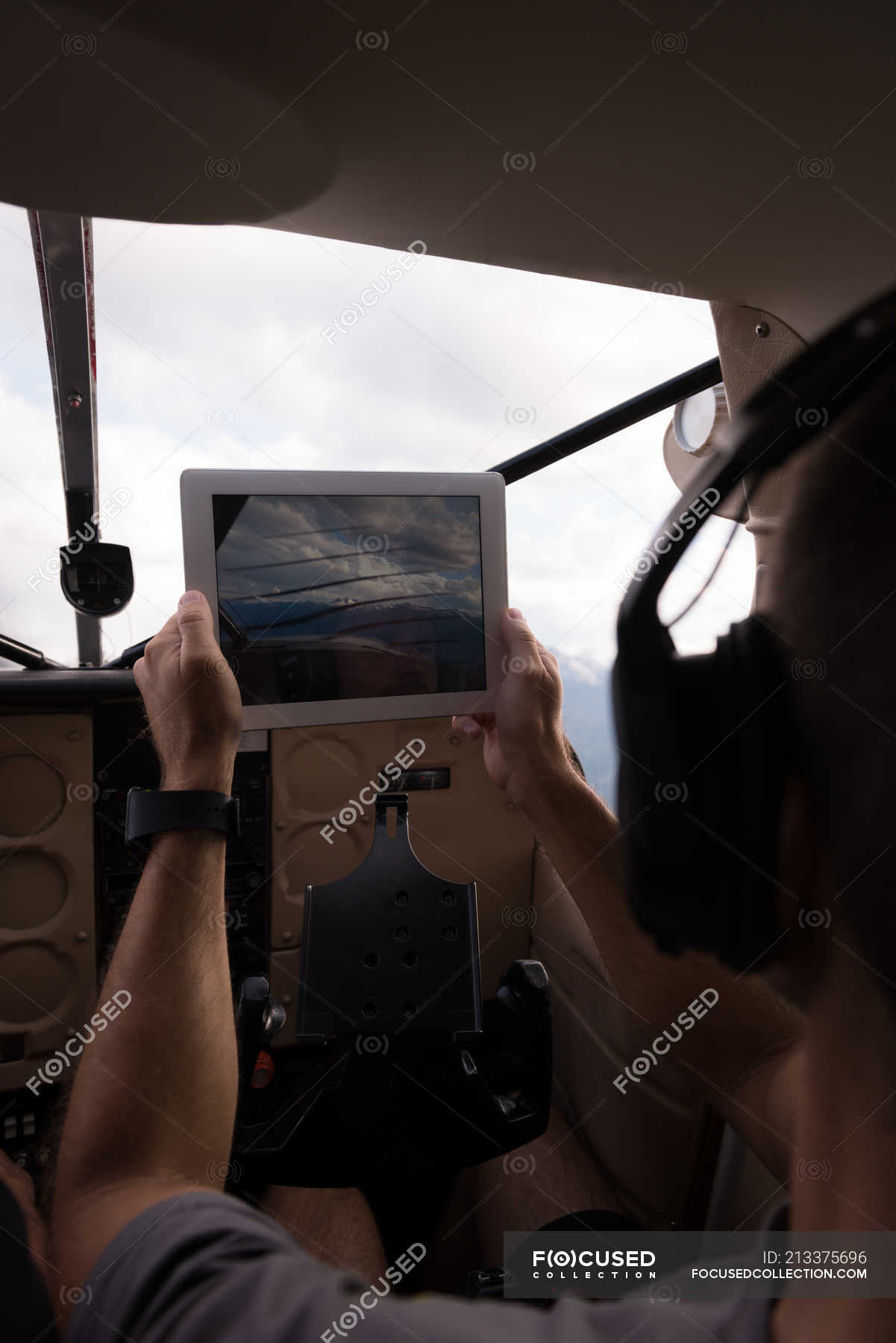 Pilot taking photos with digital table while flying in aircraft cockpit ...