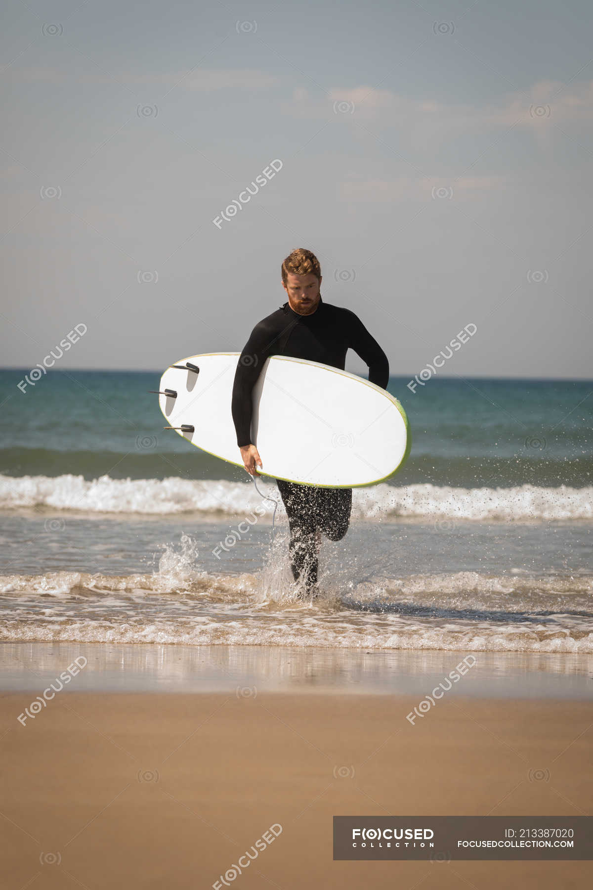 Surfer with surfboard running at beach on sunny day — vacation, horizon ...