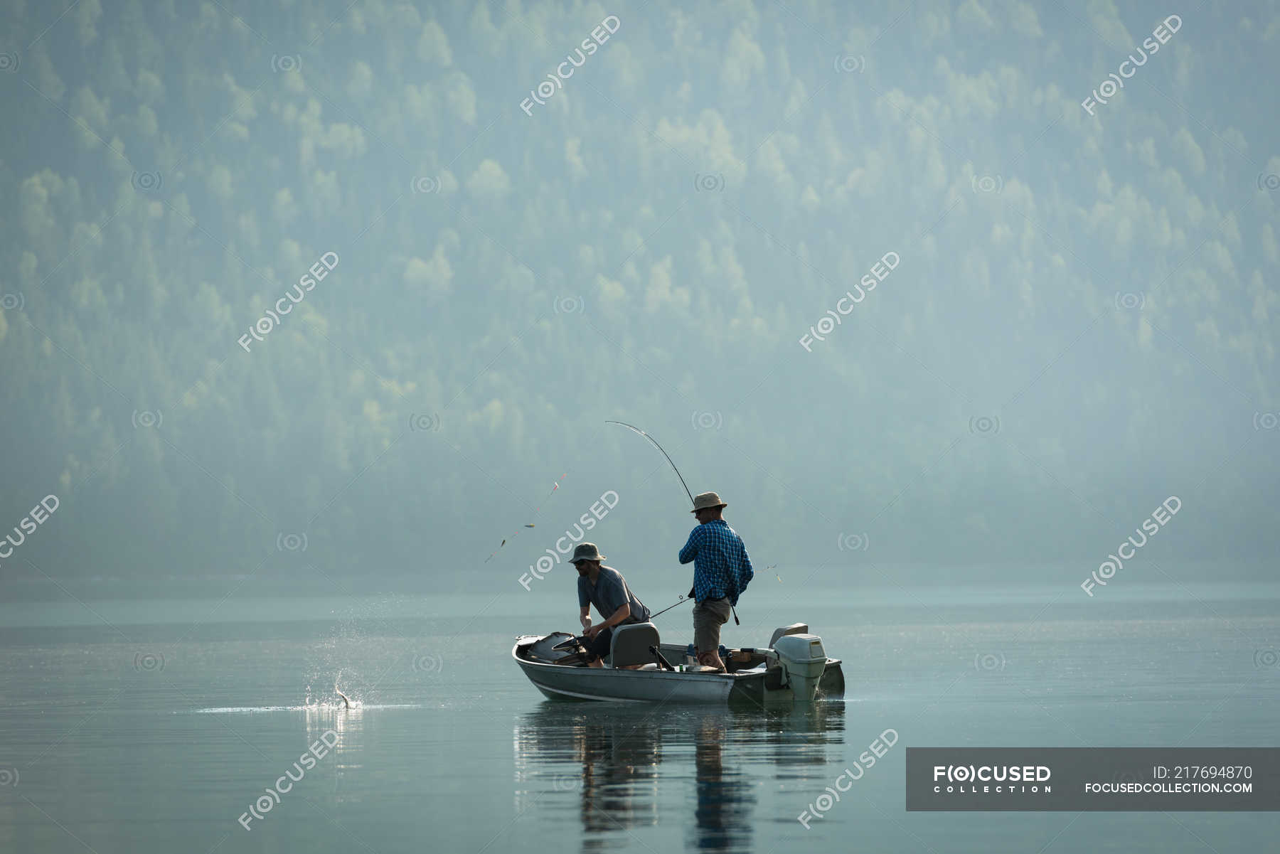 Two fishermen fishing in the river on a sunny day — standing ...