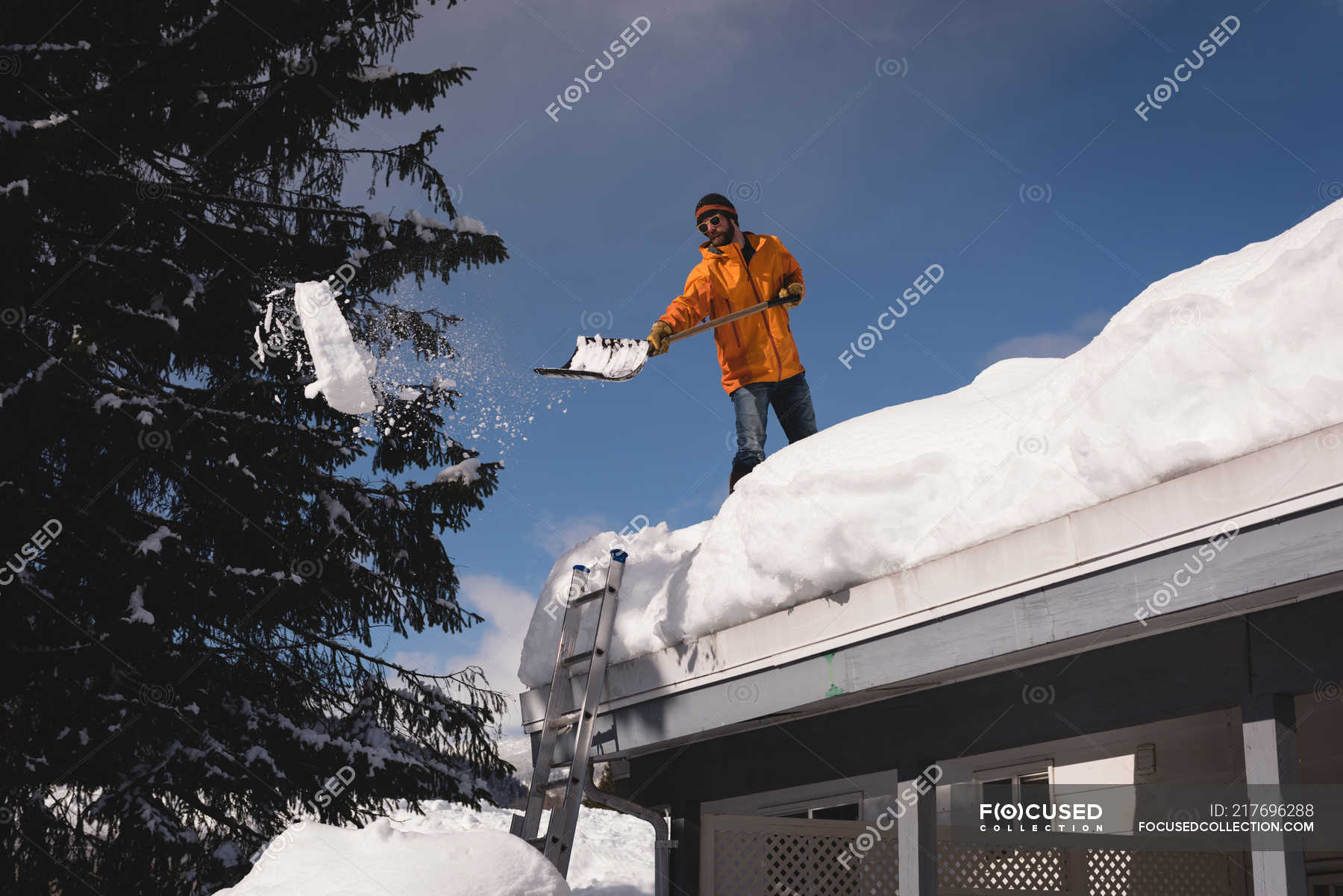 Man cleaning snow from roof top of his shop during winter — occupation ...