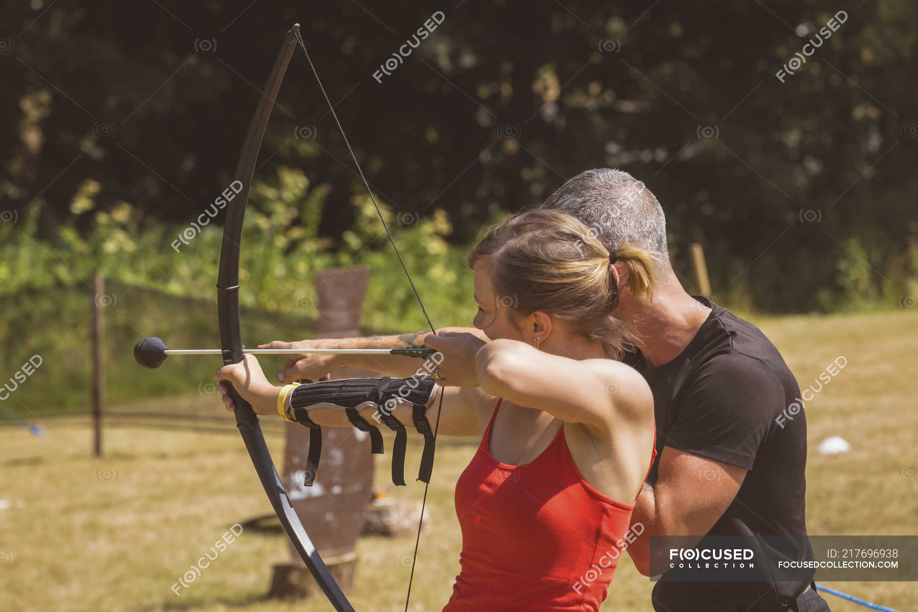 Trainer Instructing Woman About Archery At Boot Camp — Sports Arrow