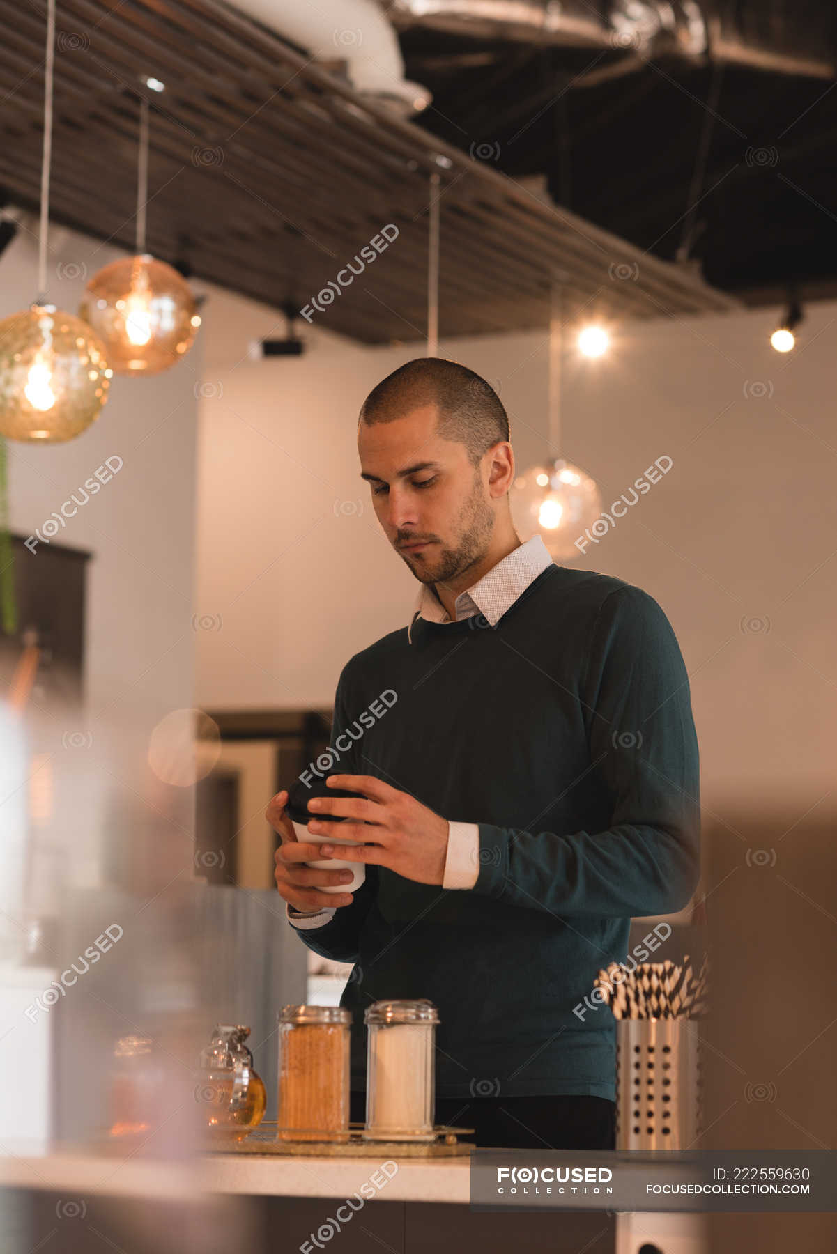 Man looking at coffee cup in cafe interior — comfortable, 25 29 Years
