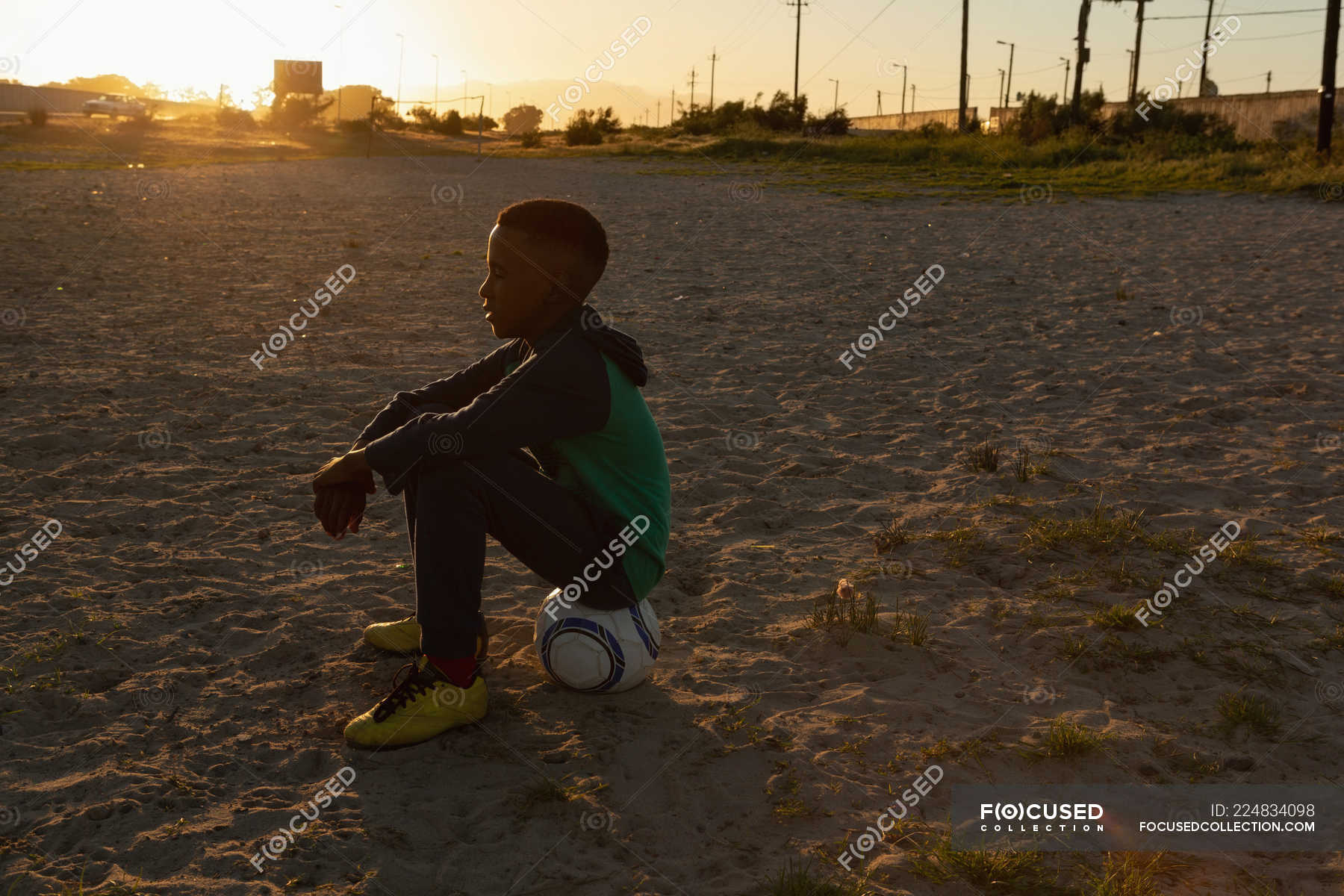 Boy sitting on football in the ground at dusk — field, soccer - Stock ...