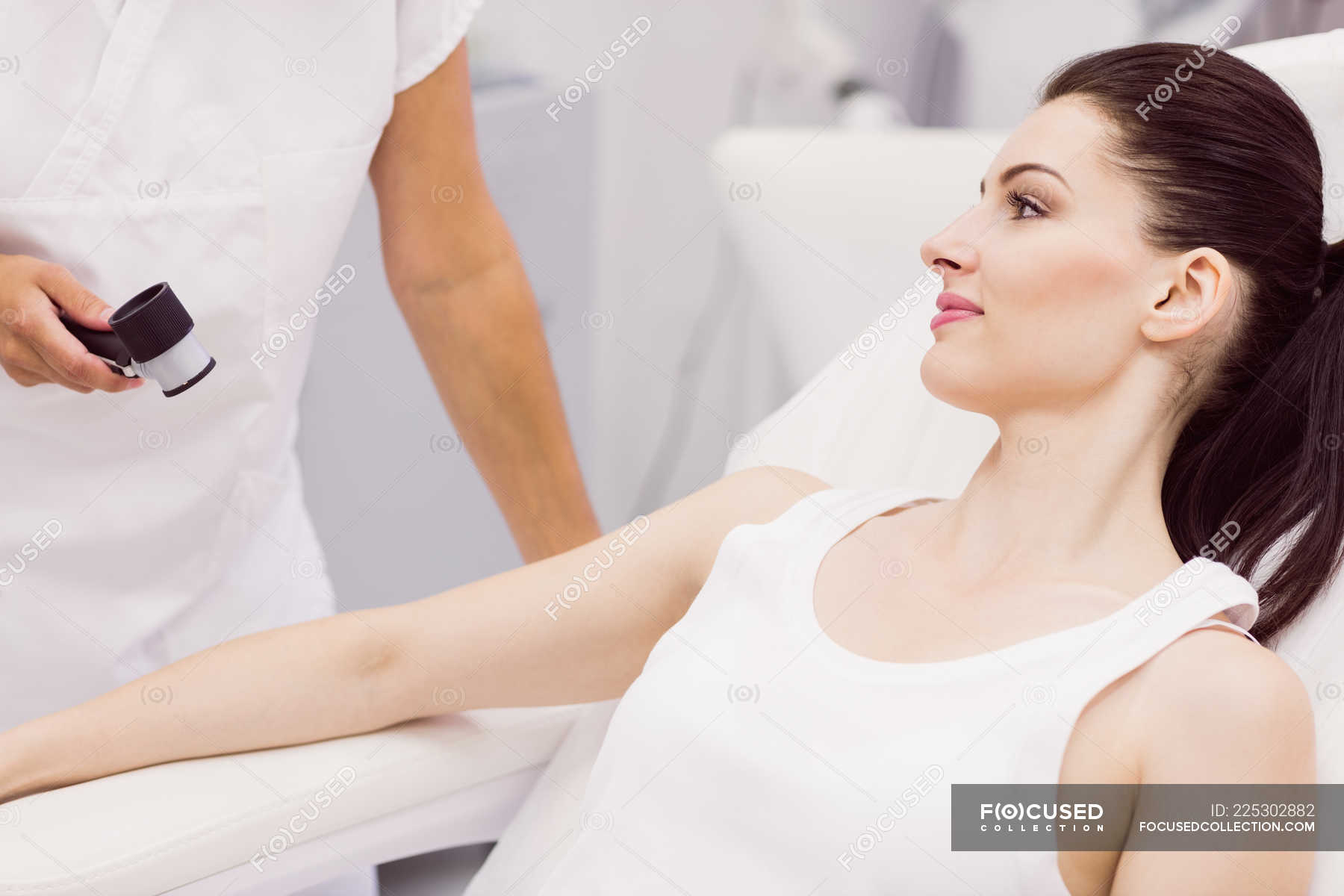 Dermatologist Examining Skin Of Patient With Dermatoscope In Clinic