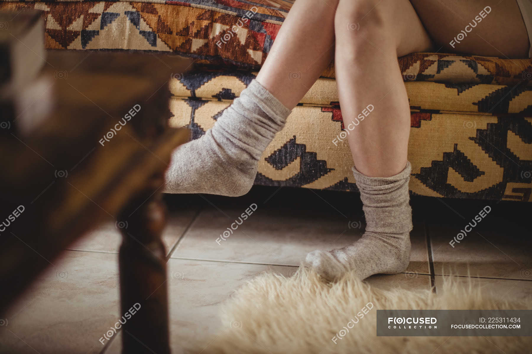 Woman Wearing Socks Sitting On Sofa With Her Legs Crossed At Home