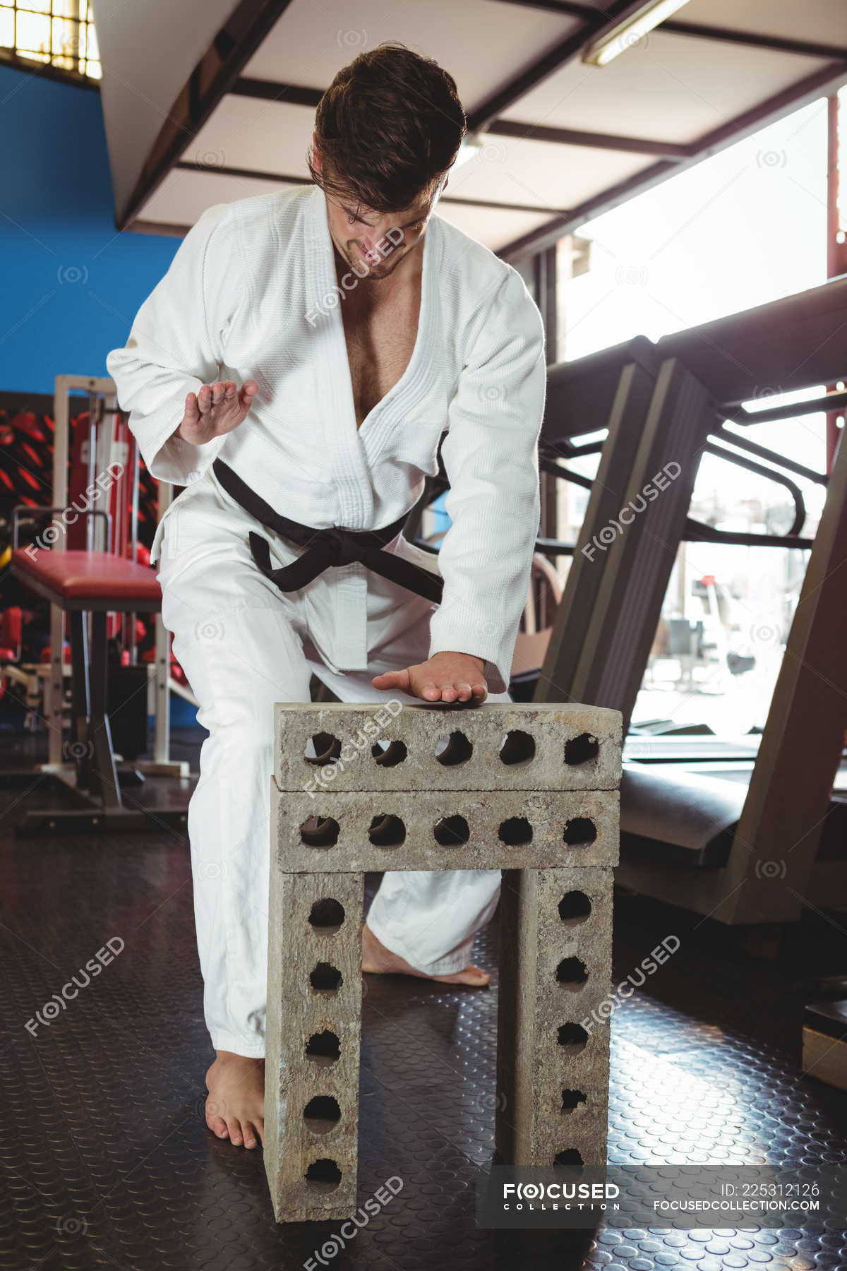 Karate player breaking concrete block in fitness studio — gym, wellness