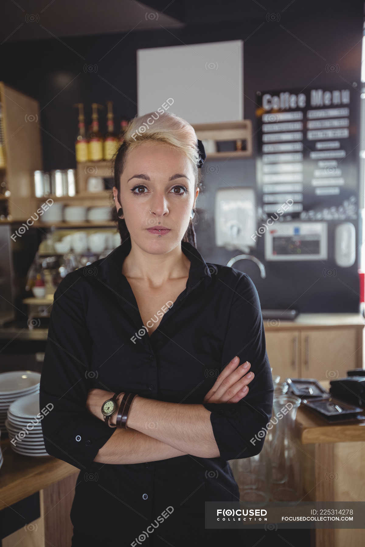 Portrait of waitress standing with arms crossed in cafe — business