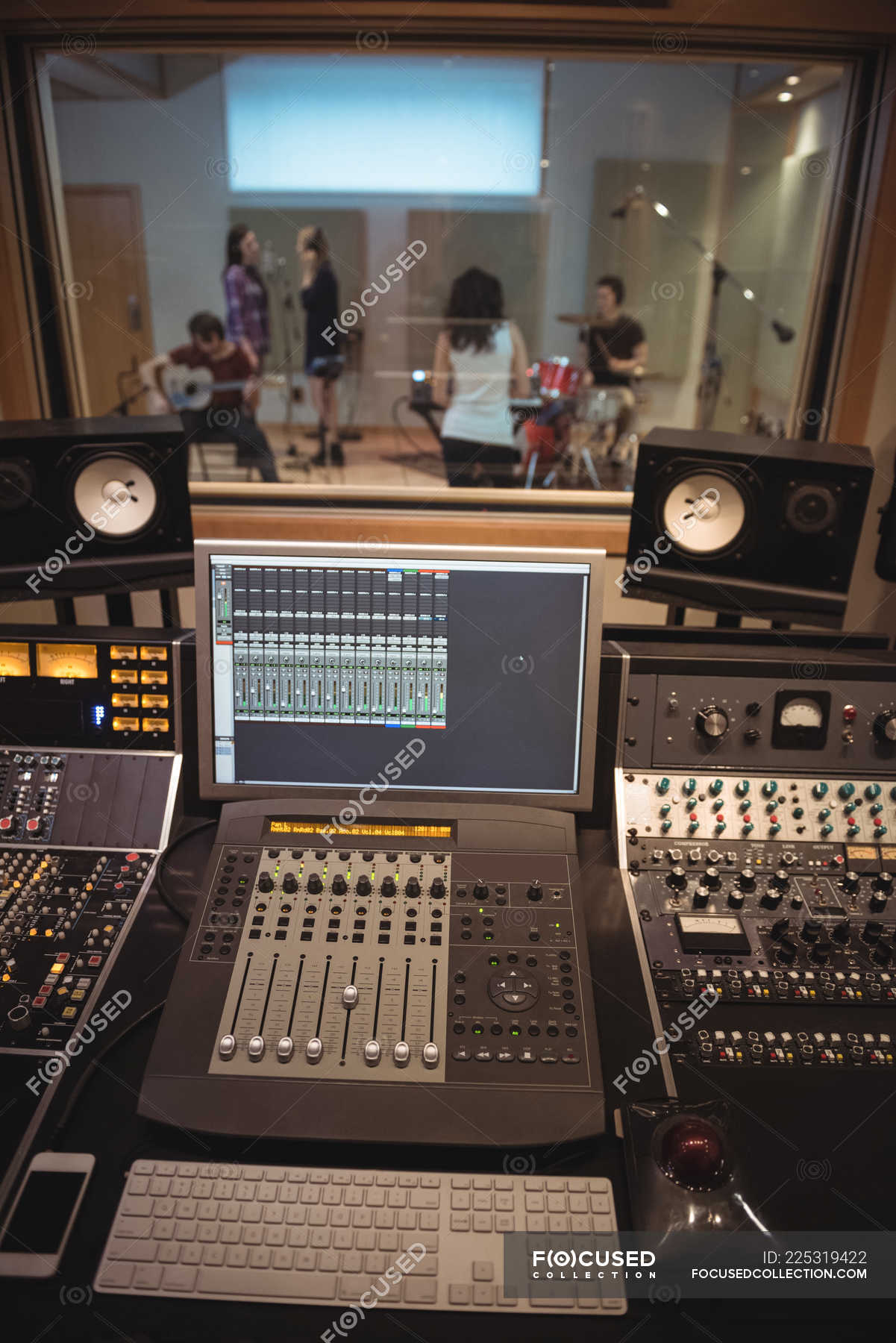 Sound mixer in a recording studio with musicians in background — monitor,  keyboard - Stock Photo | #225319422