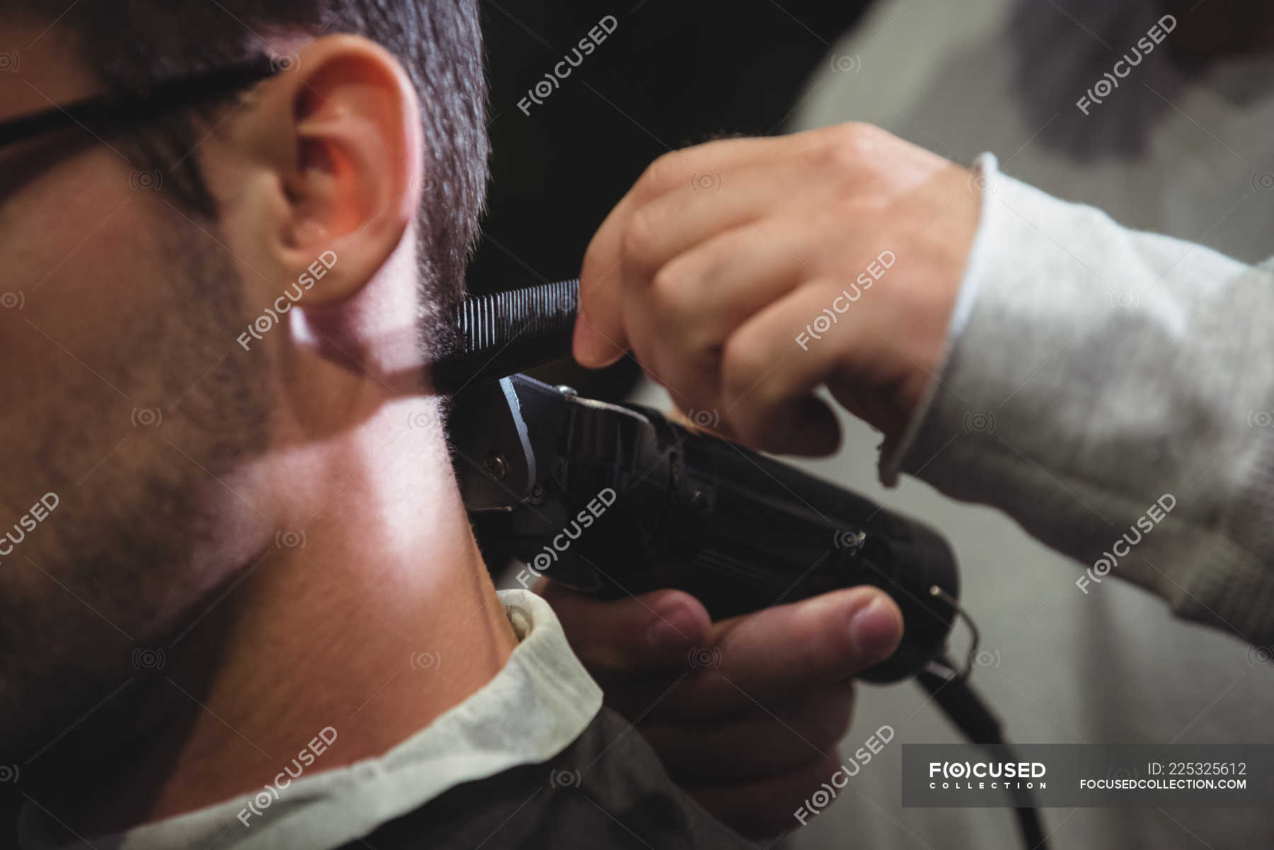 Close Up Of Man Getting Hair Trimmed With Trimmer In Barber Shop