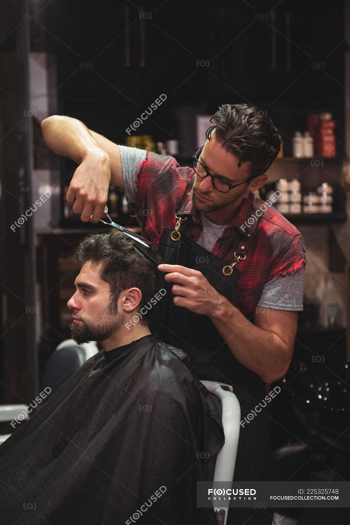 Man getting hair trimmed by hairdresser with scissors in barber shop ...