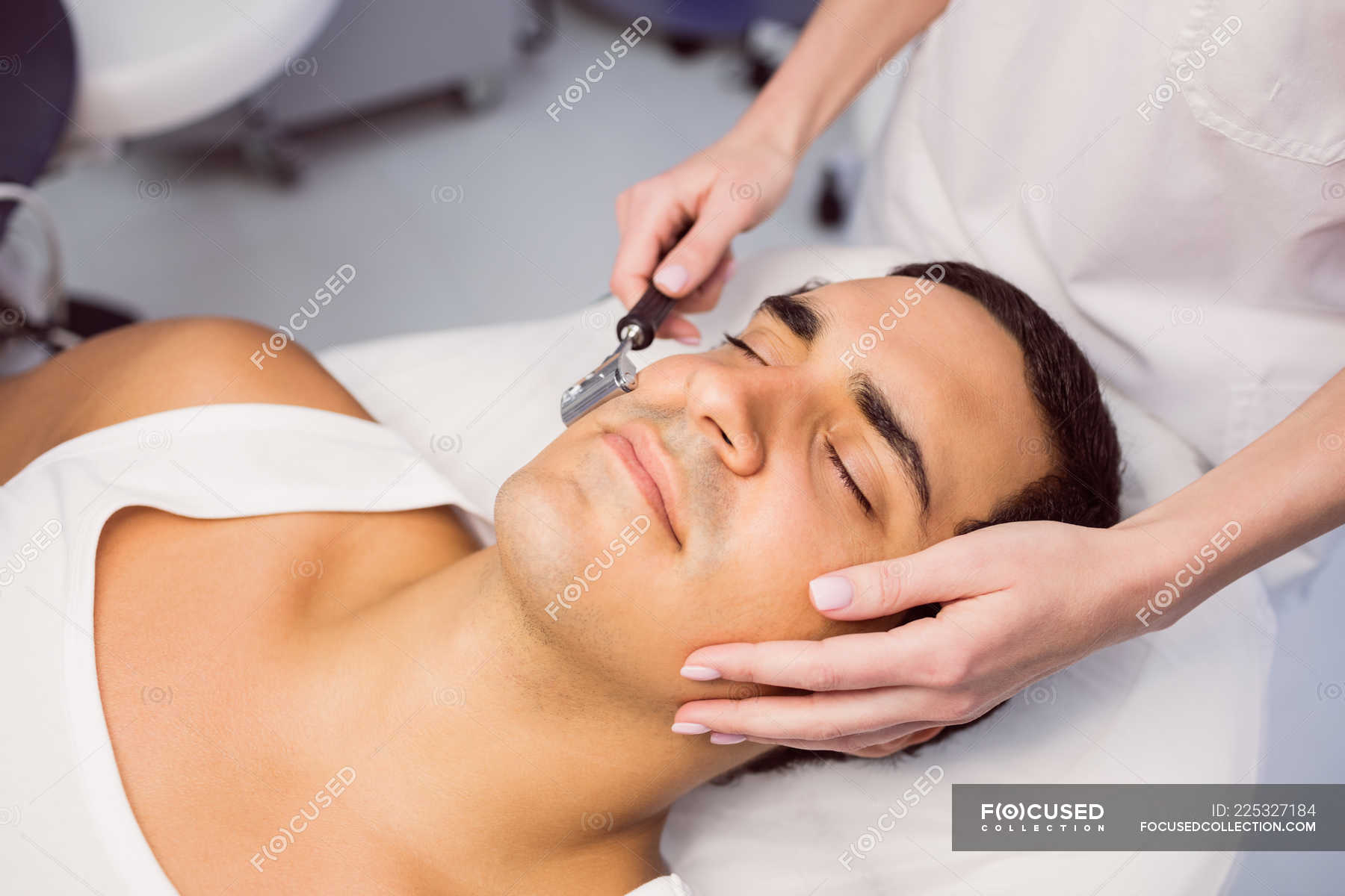 Dermatologist performing laser hair removal on patient face in clinic