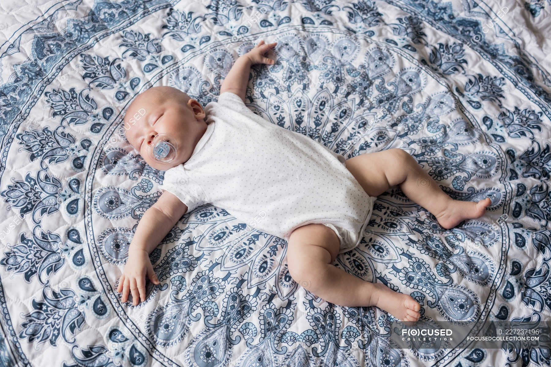 Baby sleeping with dummy in mouth on bed at home — leisure, Homey