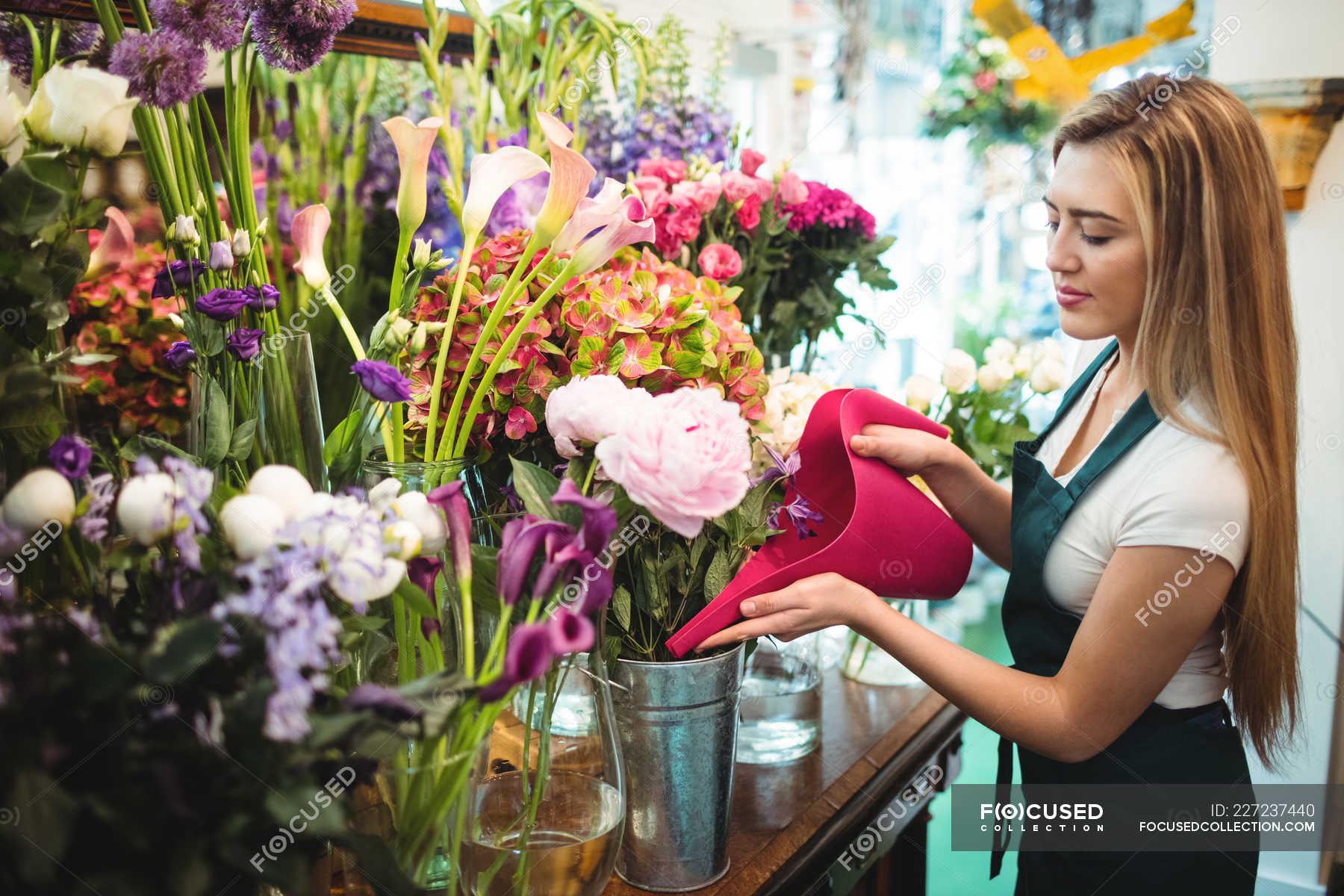 Female florist pouring water in flower vase at her flower shop