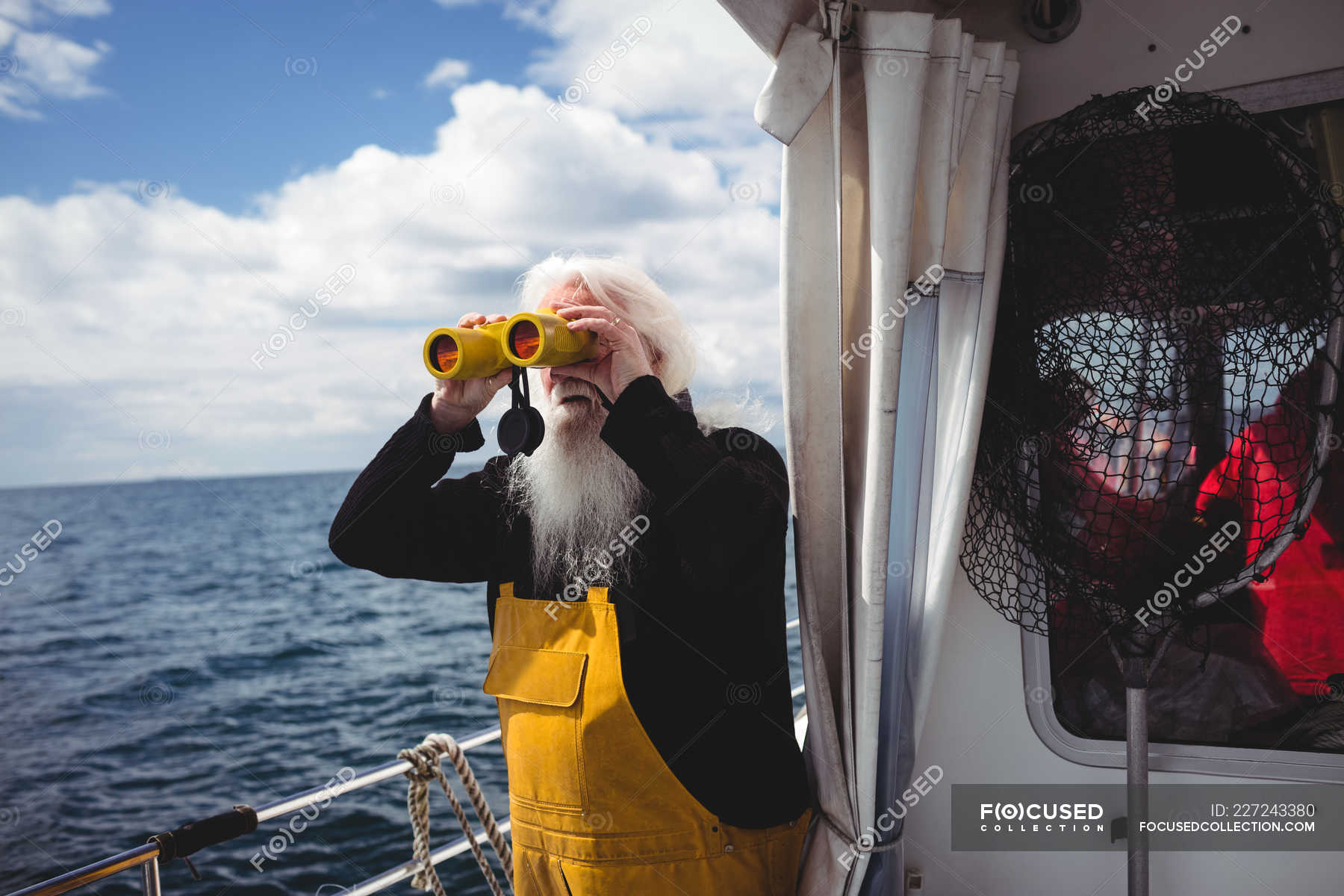 Fisherman looking through binoculars from boat — nature, holding