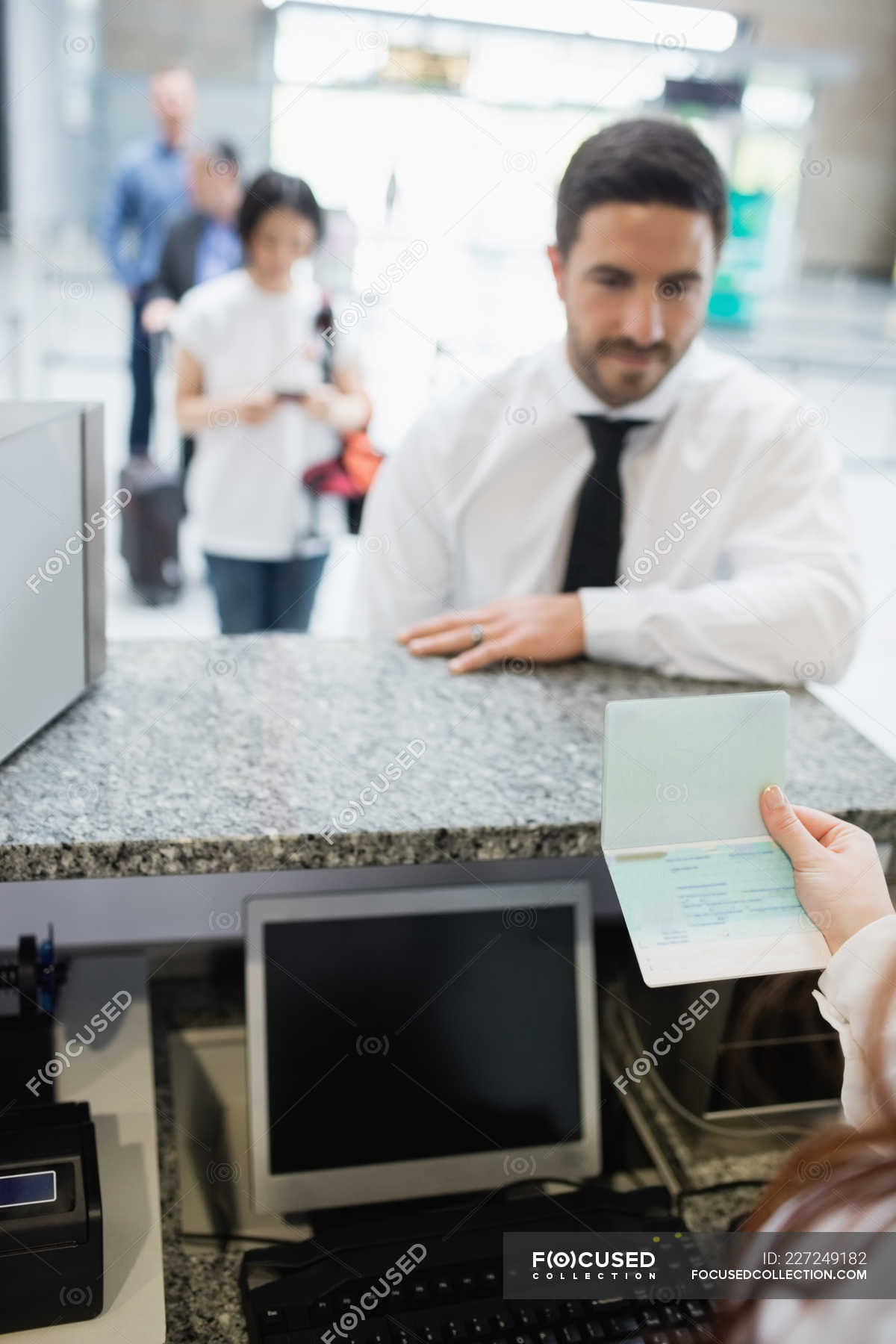 Airline check-in attendant checking passport of passenger at airport ...