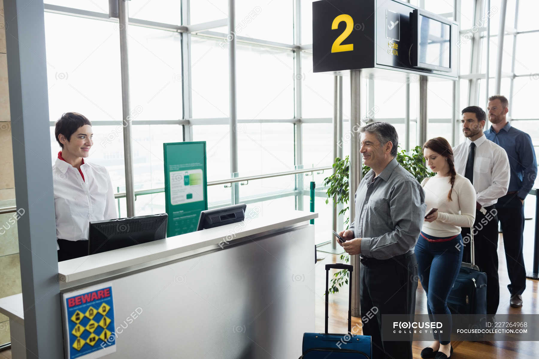 Passengers waiting in queue at check-in counter in airport terminal ...