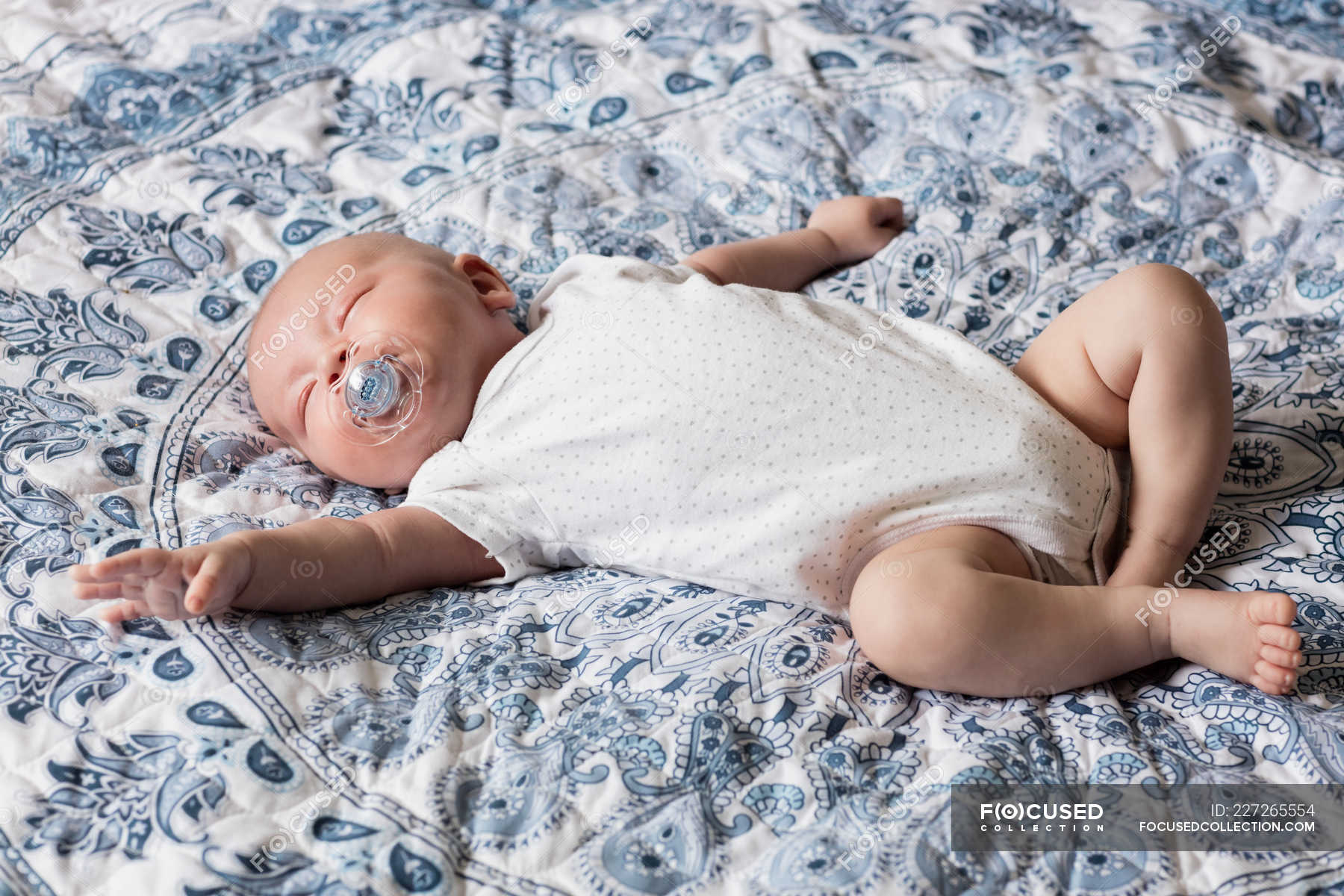 Baby sleeping with dummy in mouth on bed at home — relaxing, caucasian