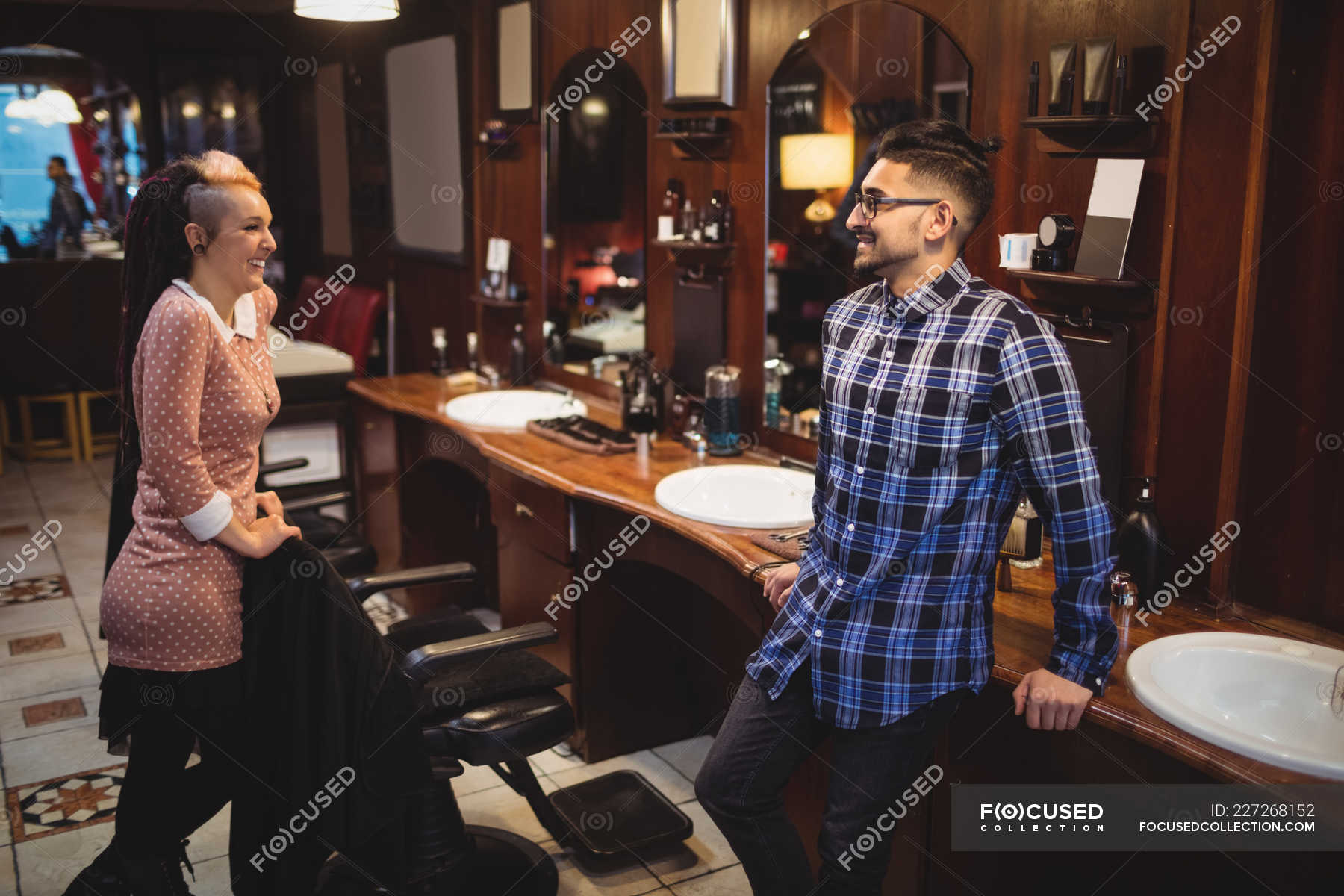 Two smiling barbers interacting with each other in barber shop — Casual ...