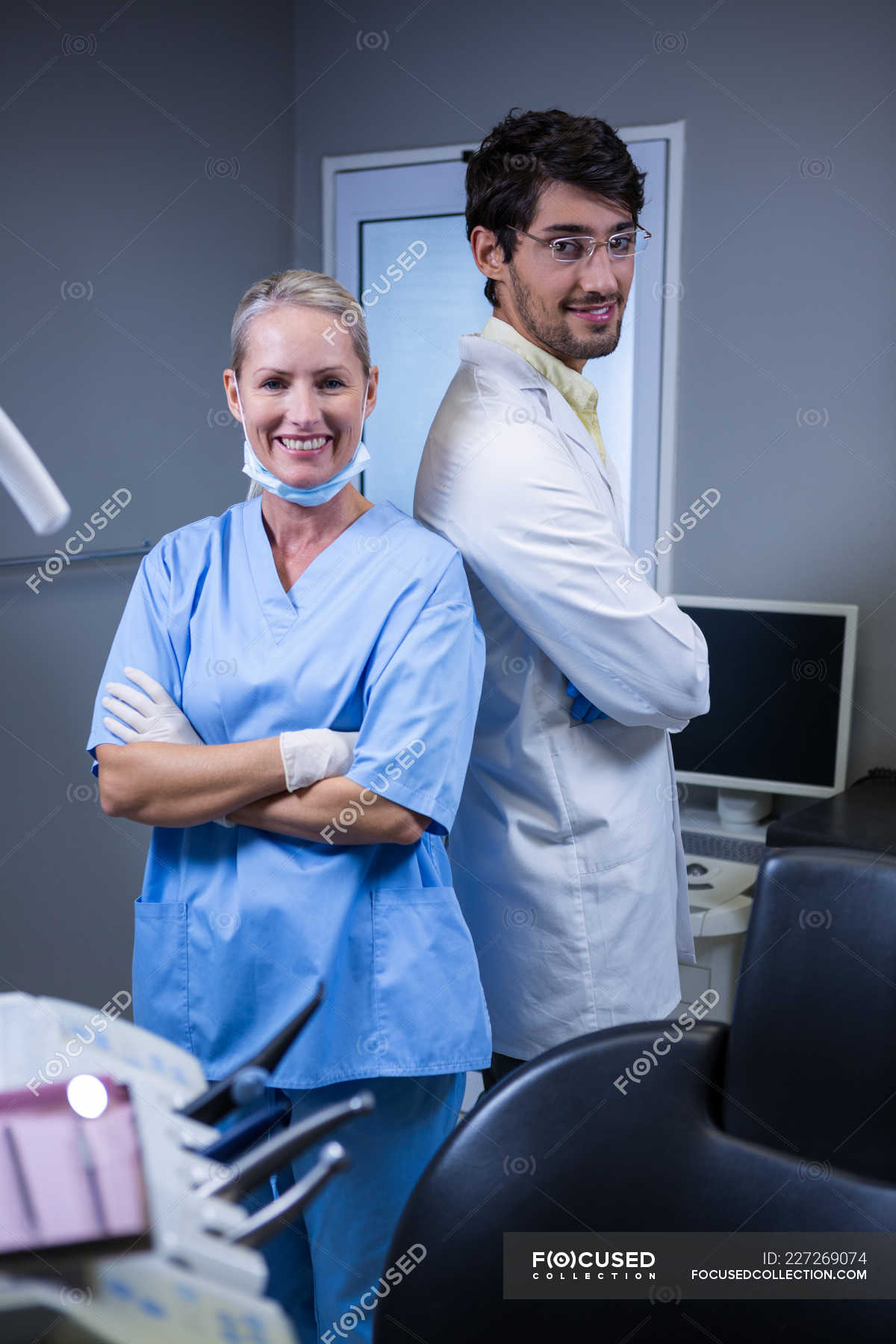Portrait Of Smiling Dentist And Dental Assistant Standing Back To