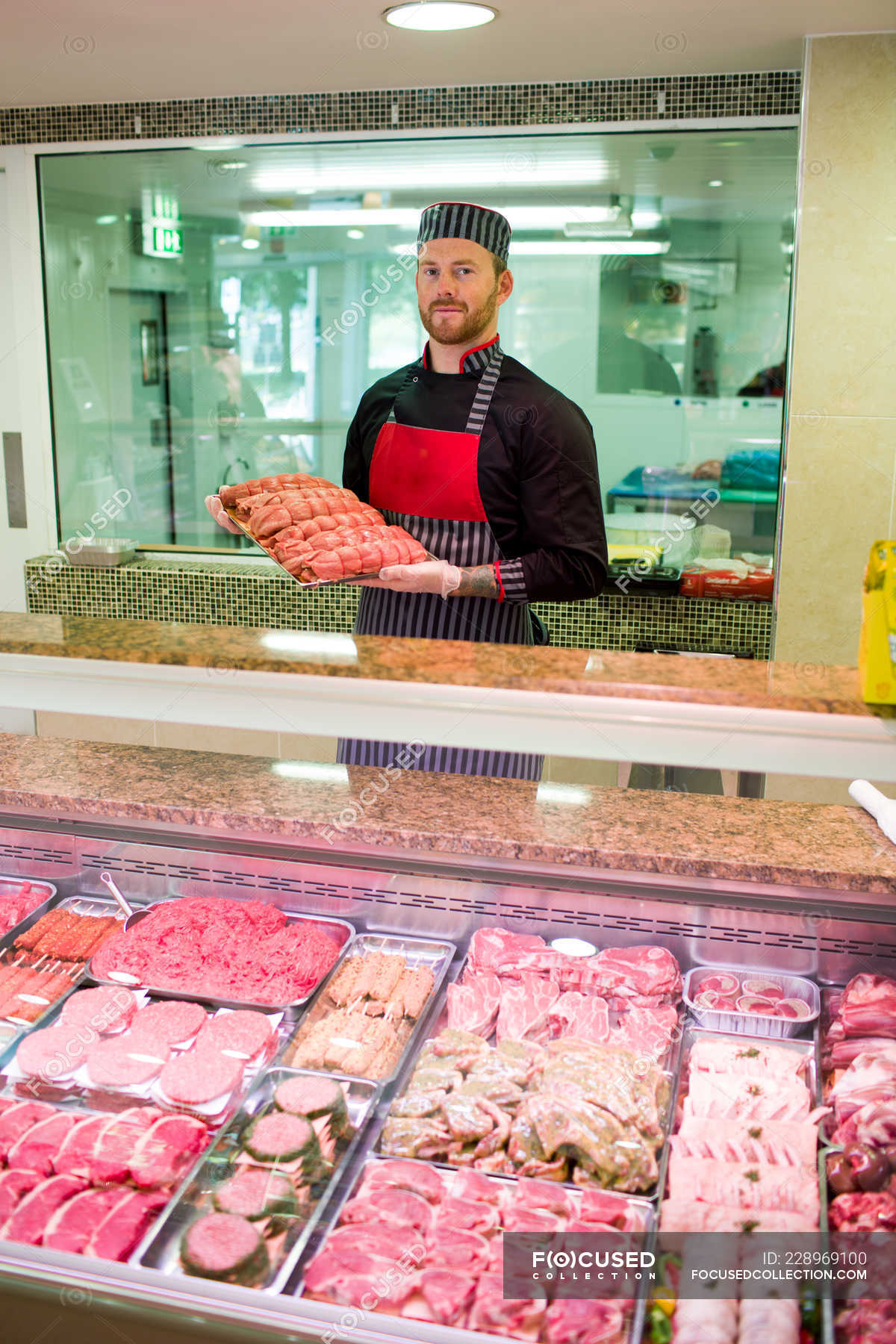 Butcher standing at meat counter in butchers shop — market, choice ...