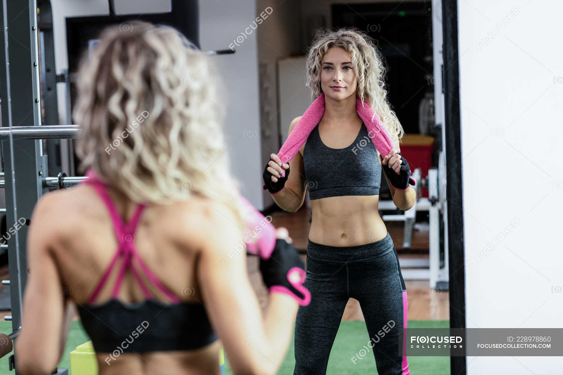 Hermosa mujer fitness con una toalla sobre su cuello entrenando en una  caminadora en el gimnasio