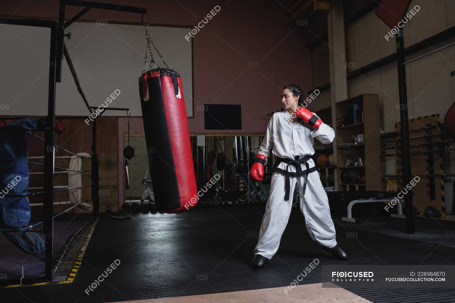 Woman practicing karate with punching bag in fitness studio — karate