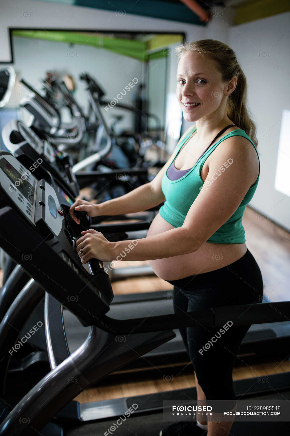 Portrait of pregnant woman exercising on treadmill at gym