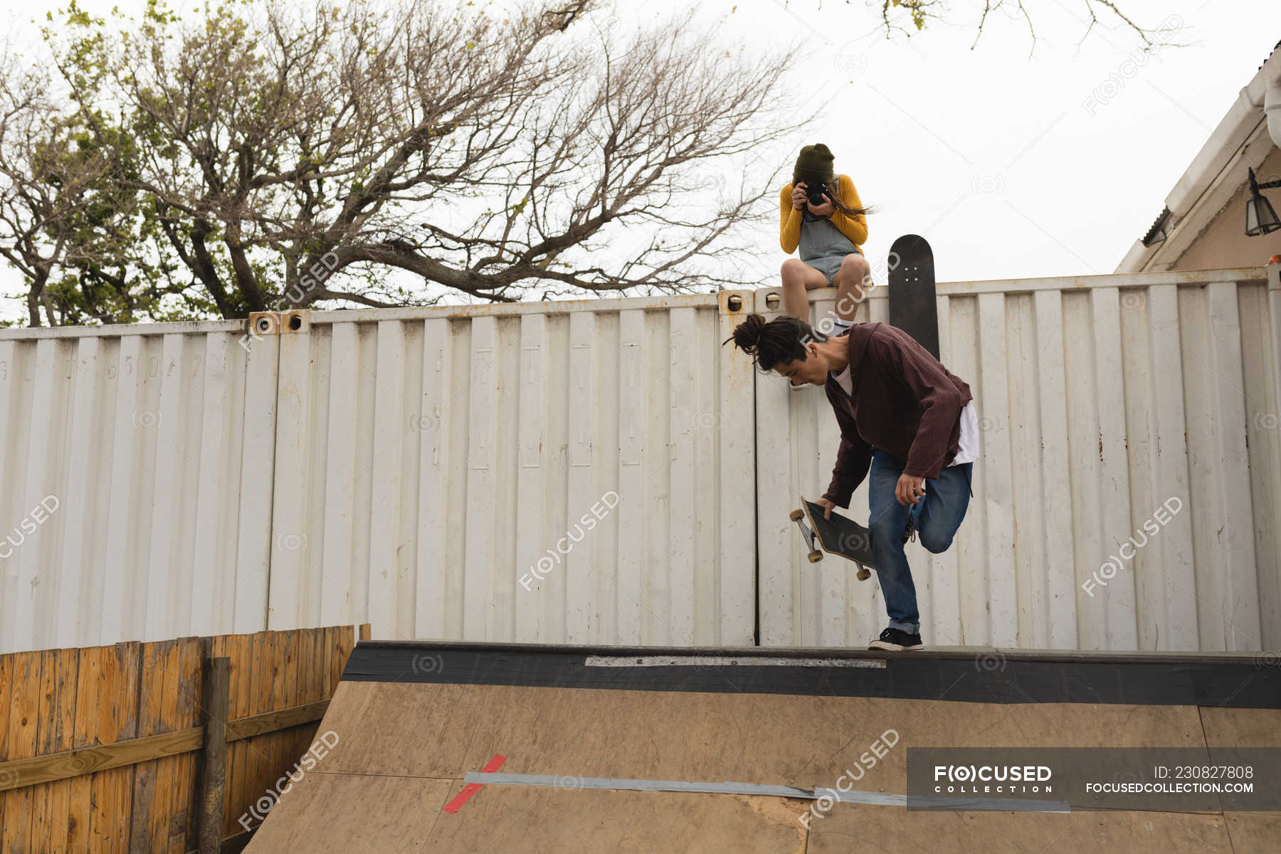 Young female skateboarder clicking photo while male skateboarder