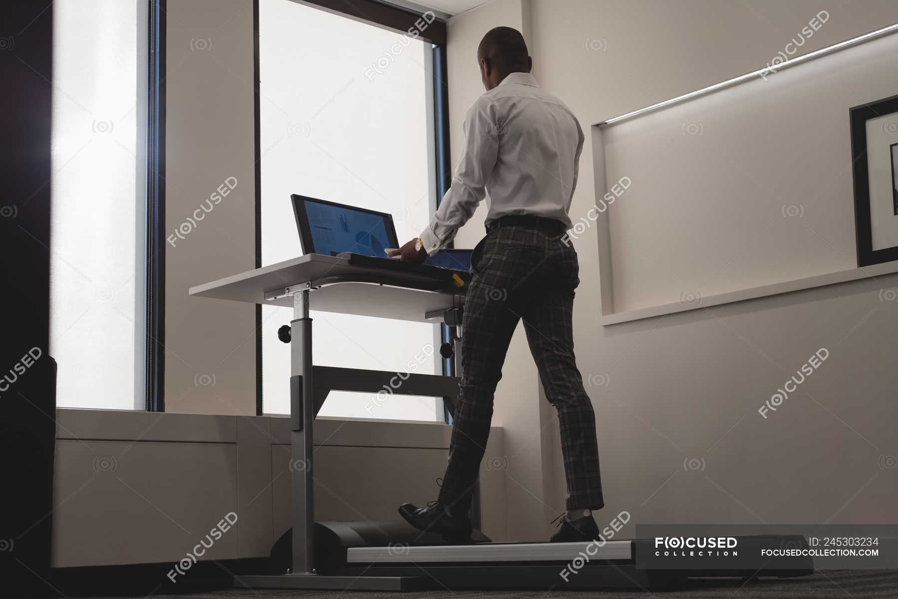Side View Of Businessman Using Laptop While Exercising On