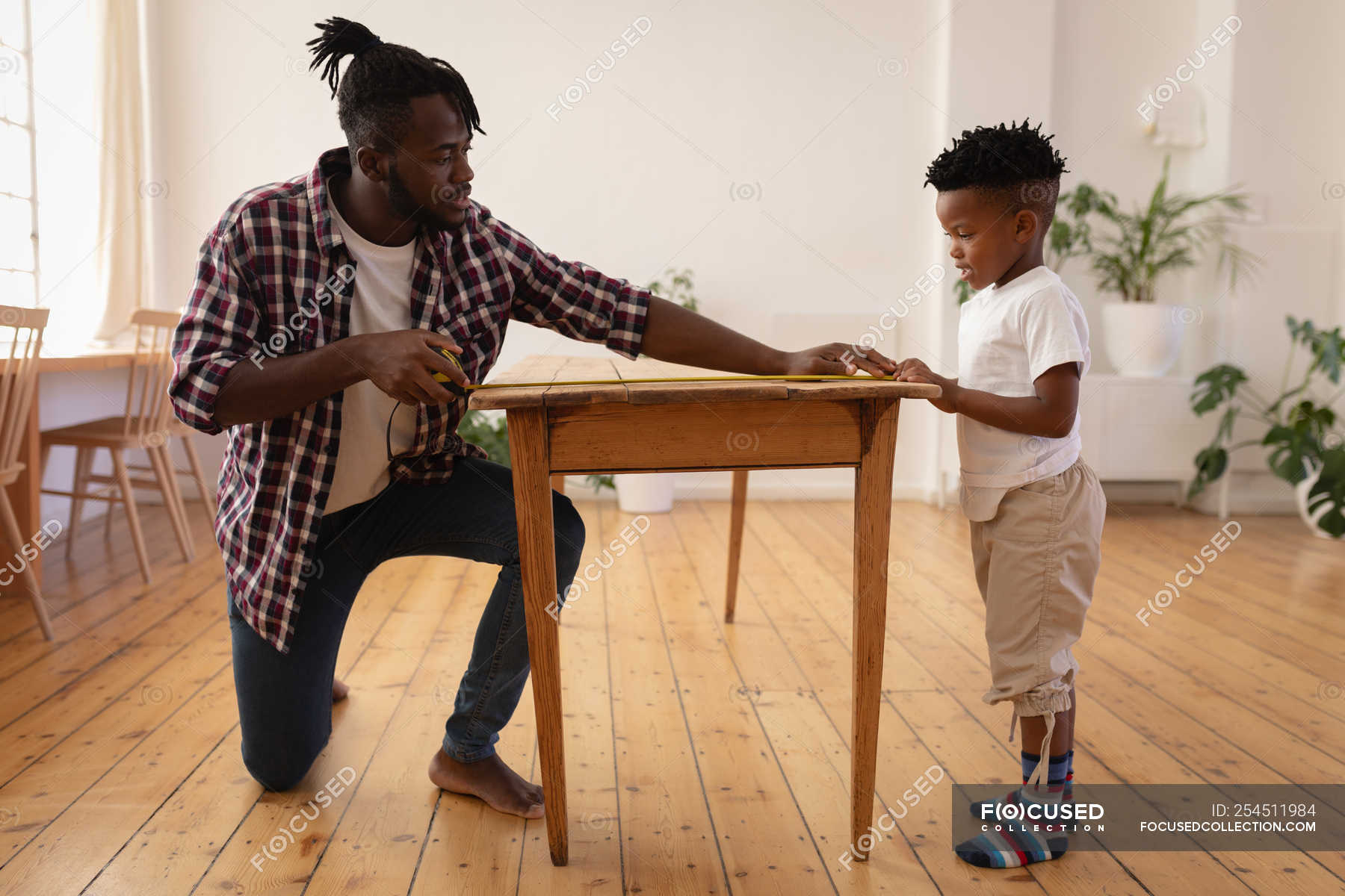 Side View Of African American Father And Son Measuring Table With