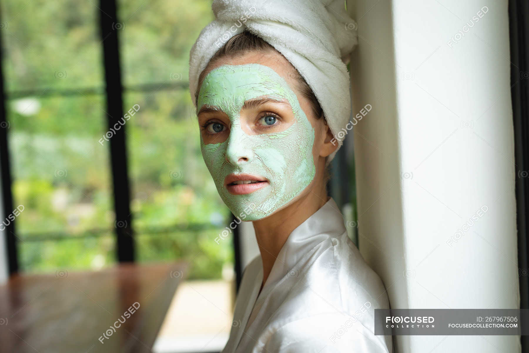 Portrait of woman in face mask looking at camera at home — standing ...