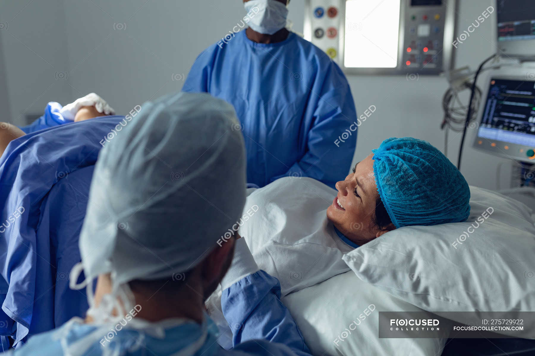 Side View Of Diverse Surgeons Examining Pregnant Woman During Delivery