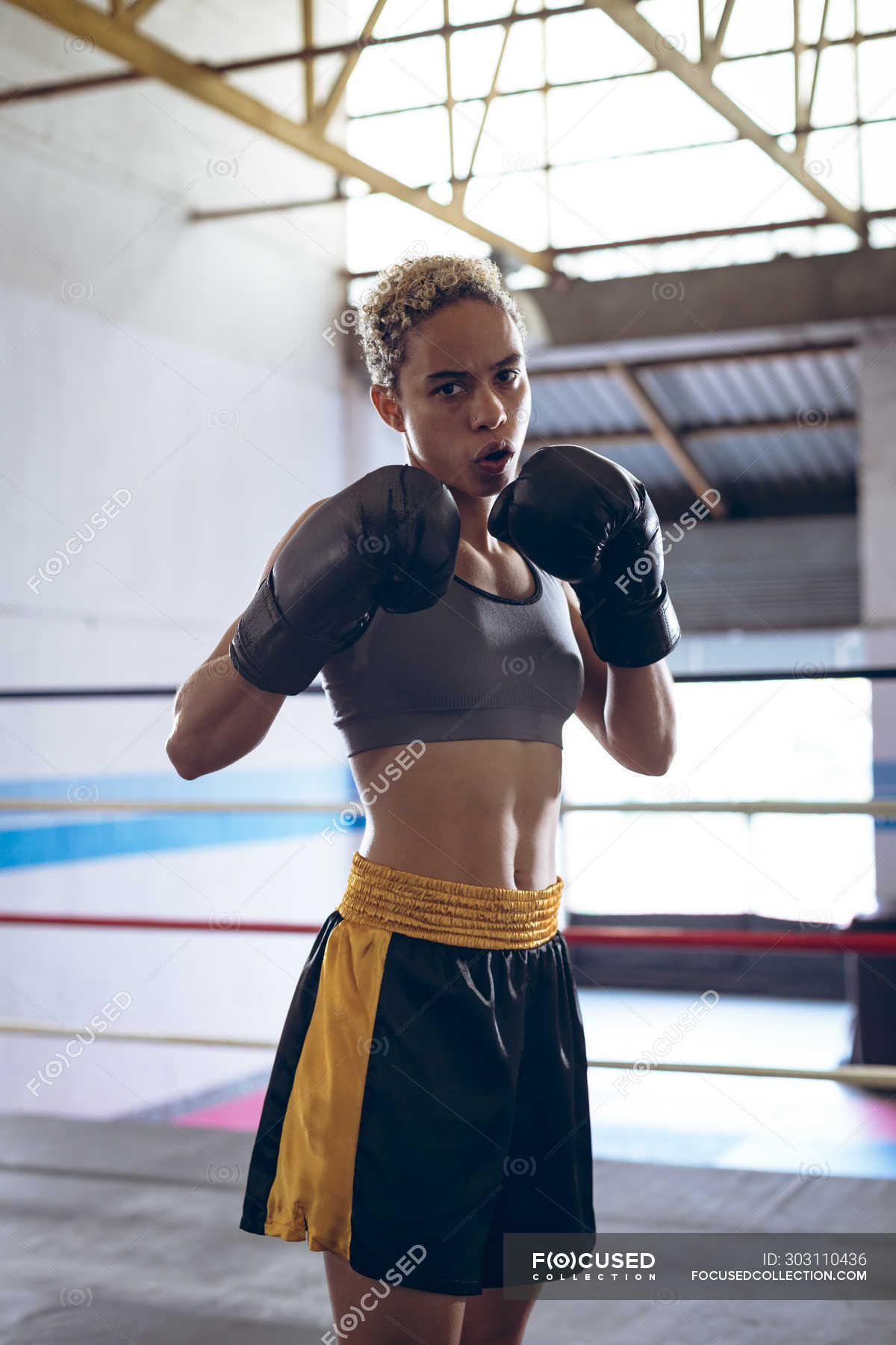 Front view of female boxer practicing boxing in boxing club. Strong female  fighter in boxing gym training hard. — looking, healthy - Stock Photo |  #303110436